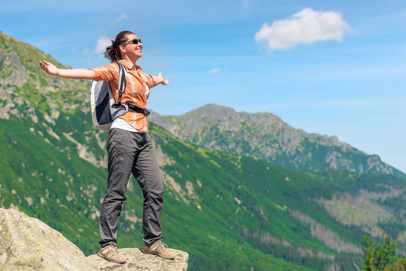 happy woman conquered a high mountain with a backpack enjoys freedom