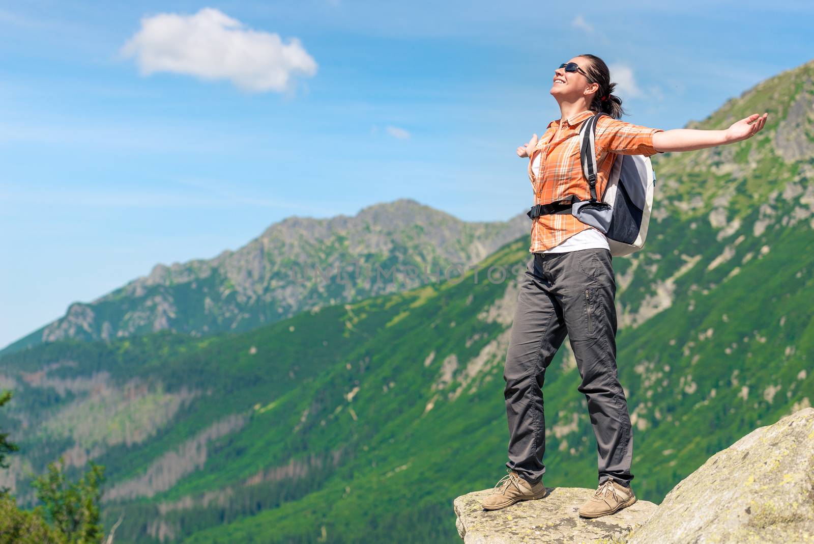 portrait of a happy woman conquering a high mountain with a backpack enjoying freedom