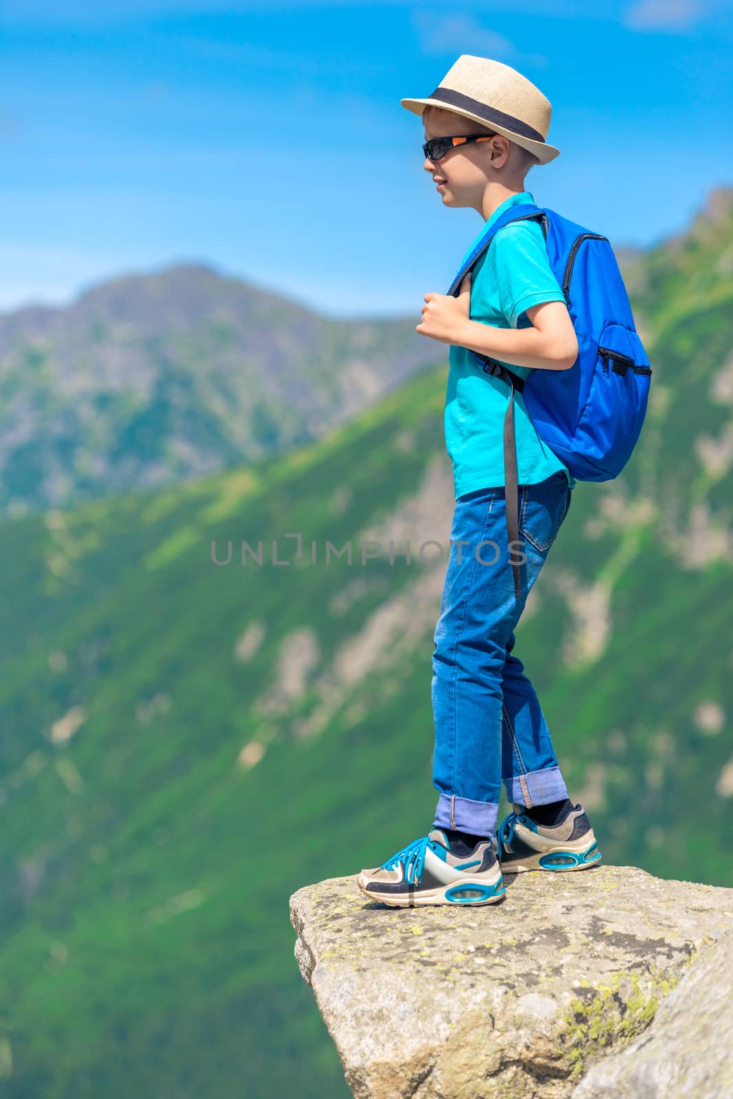 portrait of a young traveler with a backpack high in the mountains on a rock