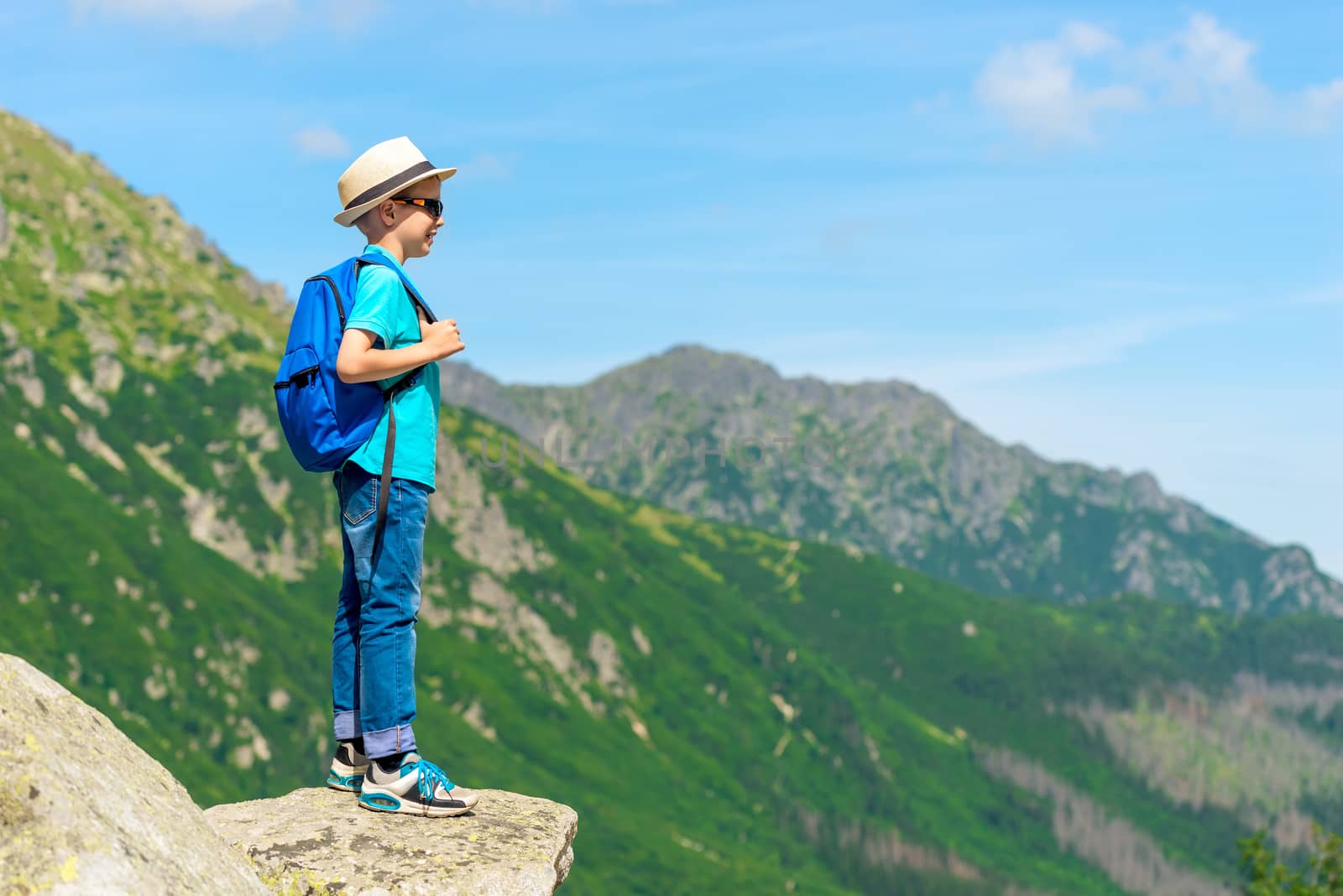 horizontal portrait of a young traveler with a backpack high in the mountains on a rock