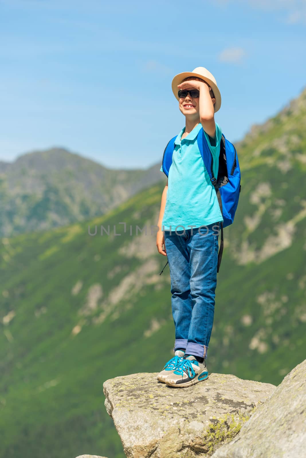 schoolboy traveler with a backpack high in the mountains on a rock