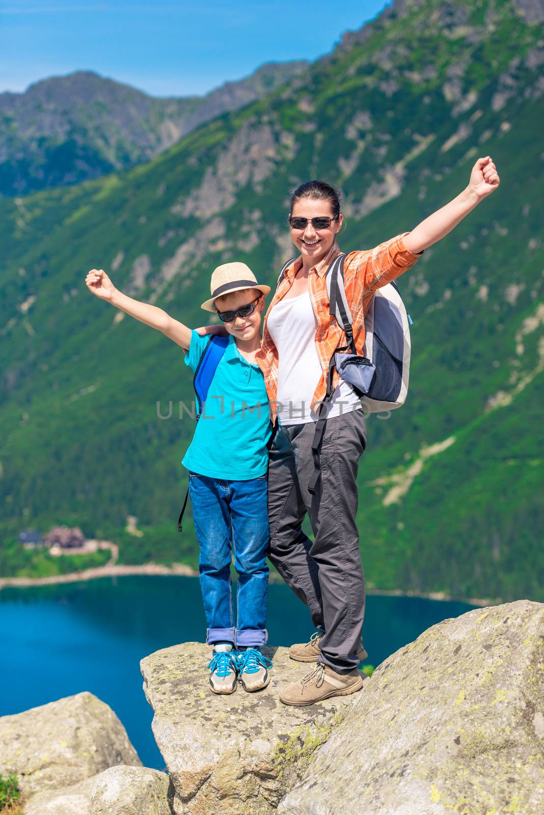 mother and son with backpacks high in the mountains against the backdrop of Lake Morskie Oko, Poland
