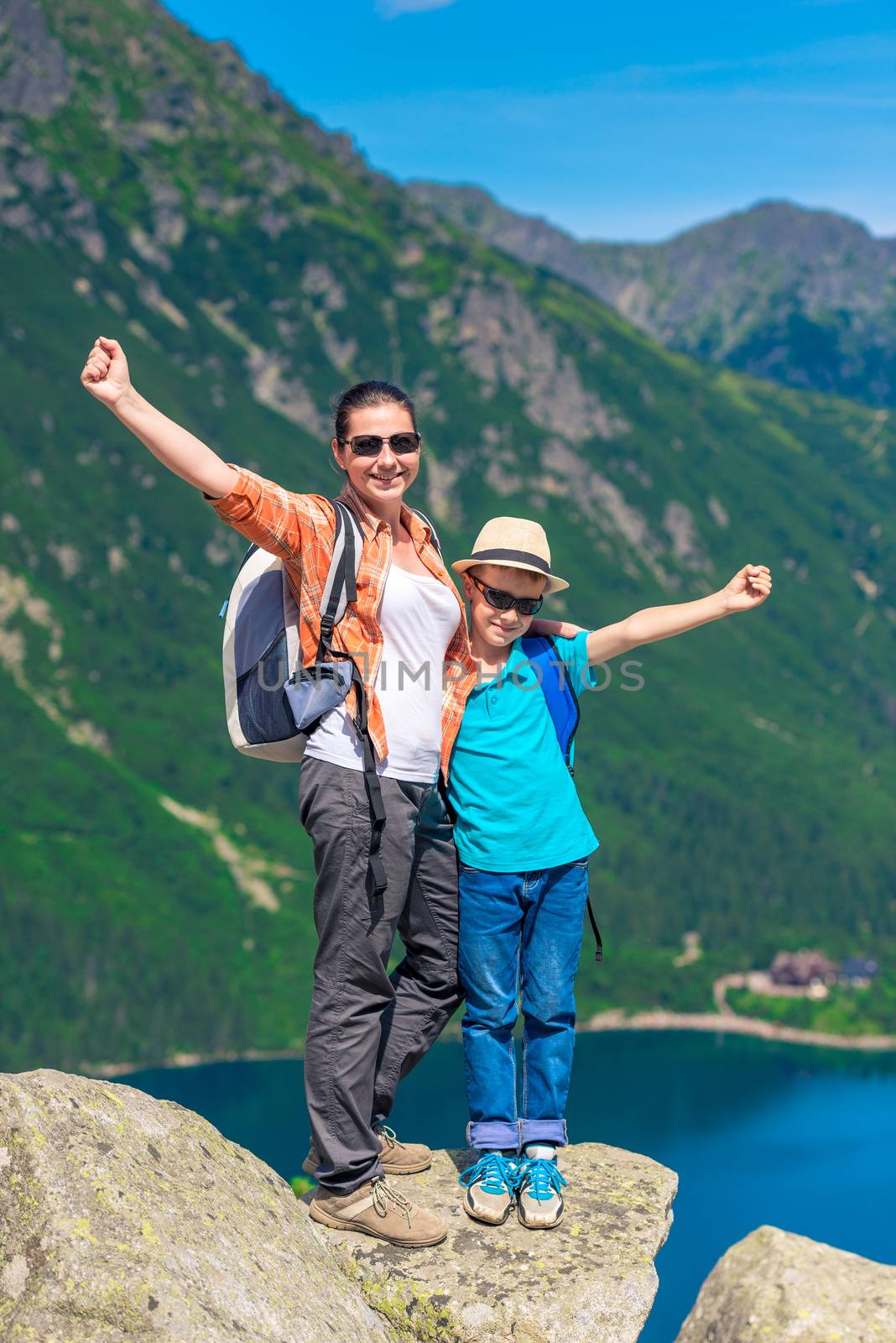 happy mother and son with backpacks high in the mountains agains by kosmsos111