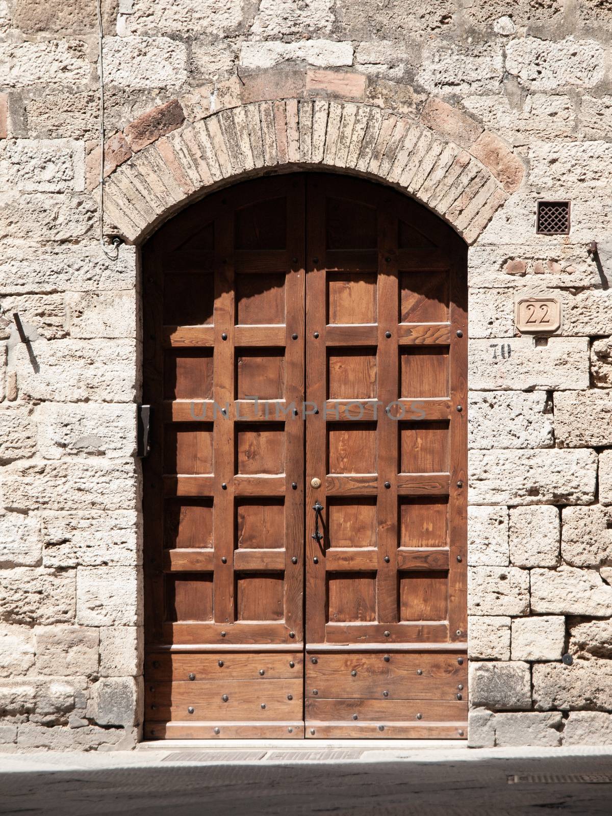 Old brown wooden door in medieval street by pyty