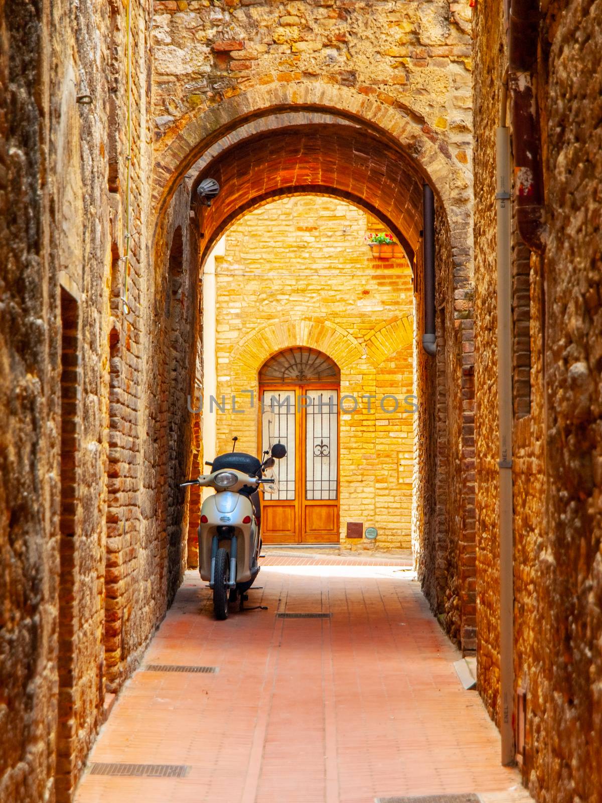 Old medieval street of San Gimignano with small motorcycle, Tuscany, Italia by pyty