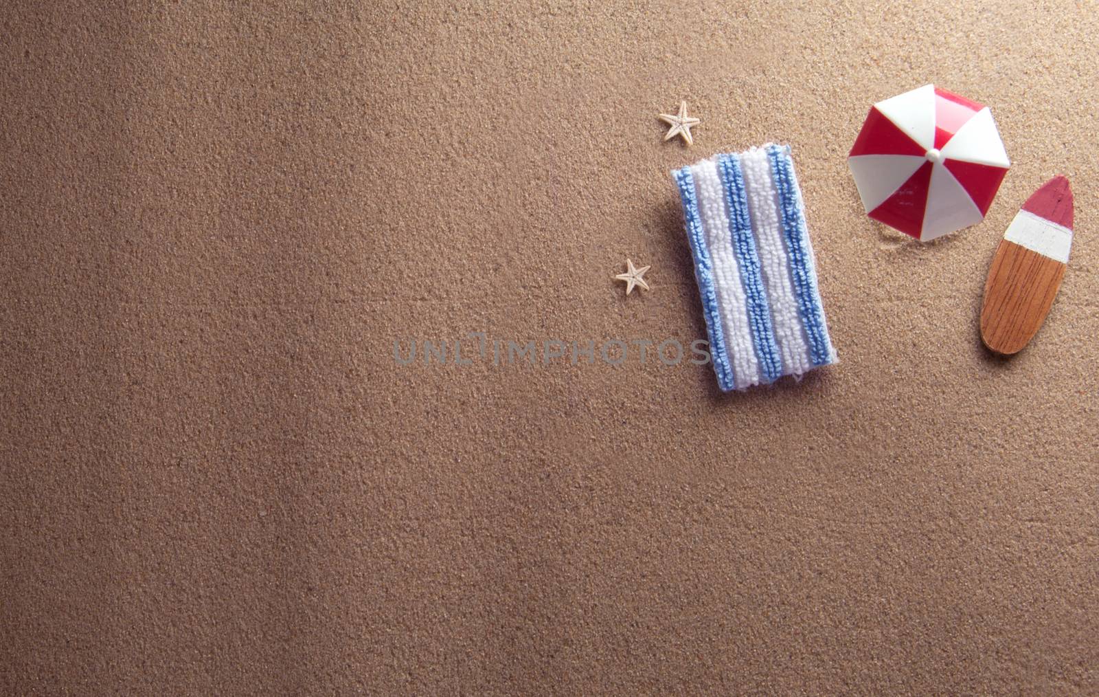 Miniature parasol and towel on beach sand