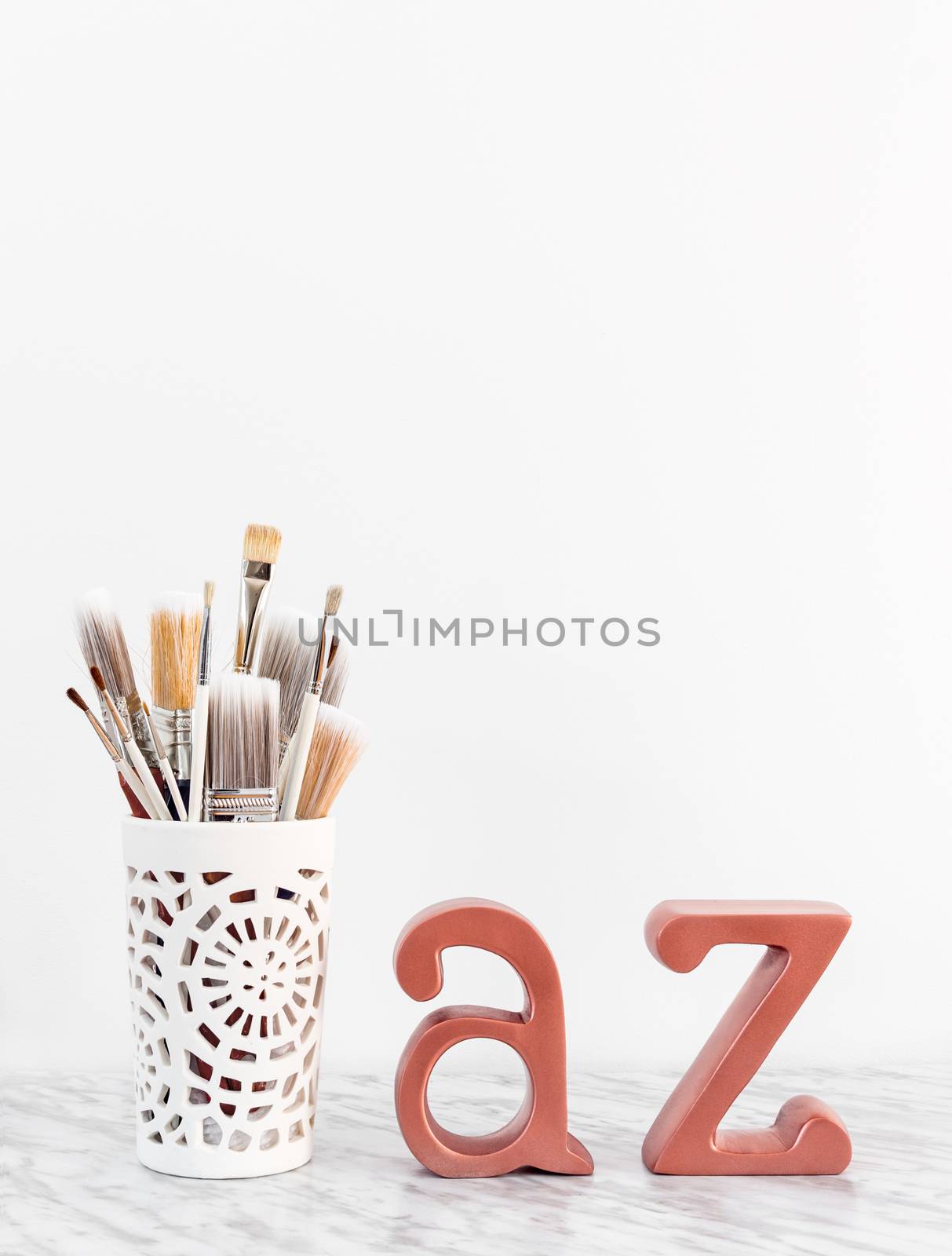 Paintbrushes with metal A and Z letters on marble surface by anikasalsera