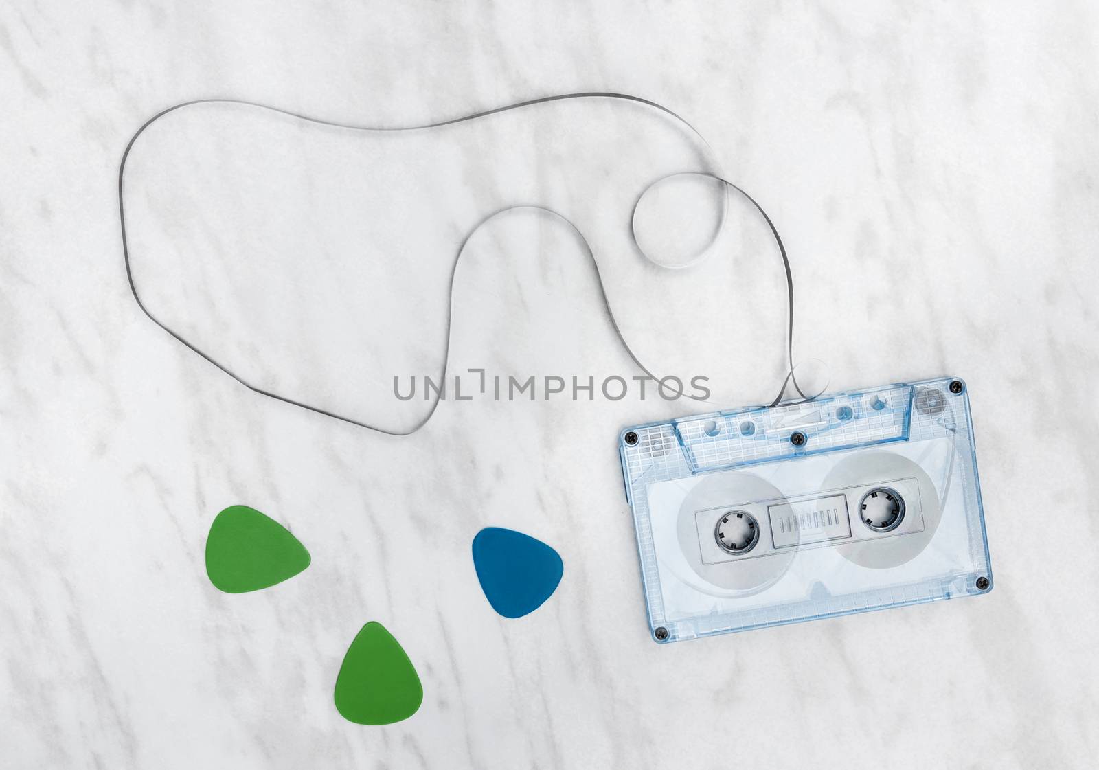 Blue audio tape and guitar picks on marble background.