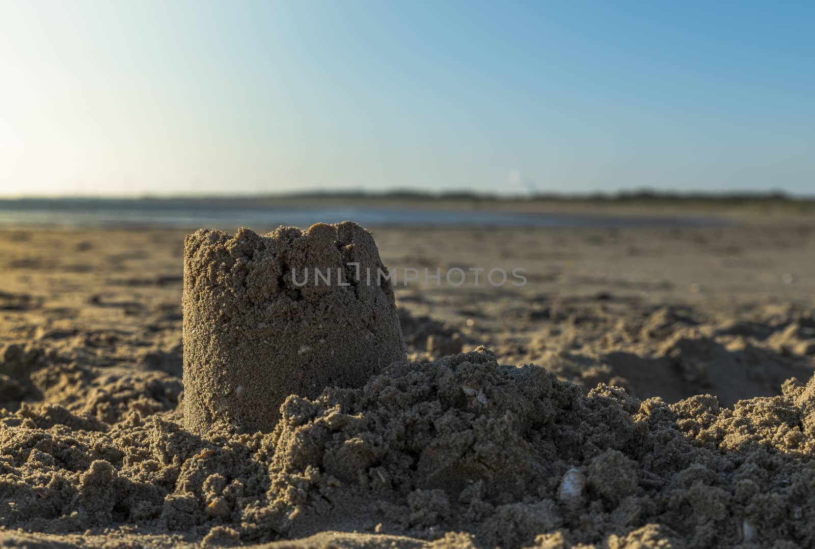 sandcastle at the beach with low sunset at the background