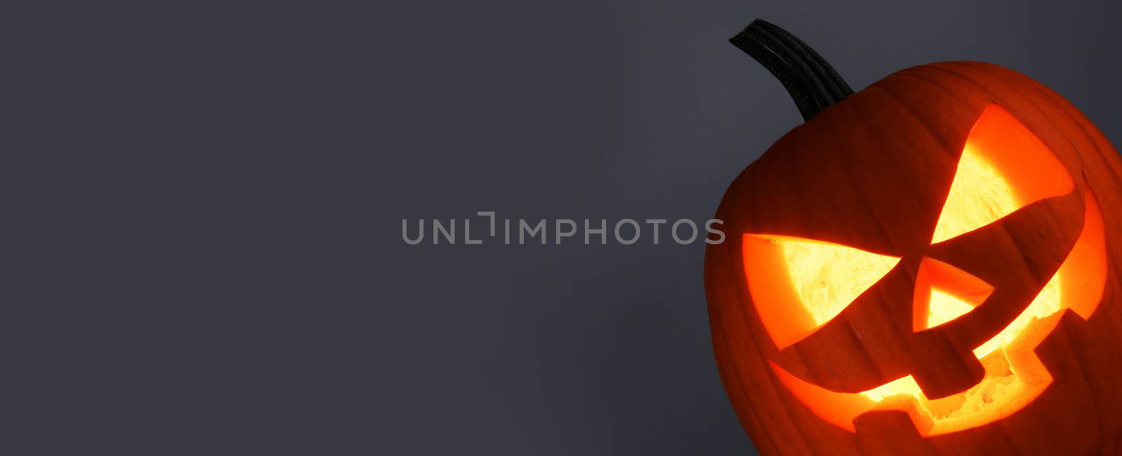 Funny glowing Halloween Pumpkin on gray background