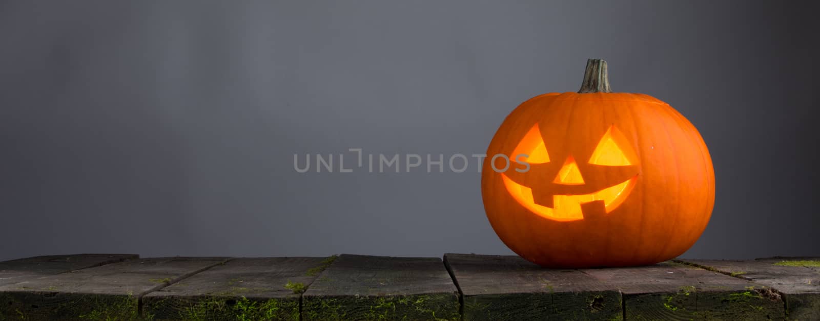 Glowing Halloween pumpkin head jack lantern on wooden table