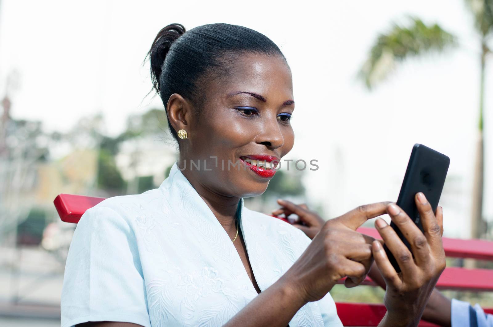 This young woman consults her phone with  smile on her face.