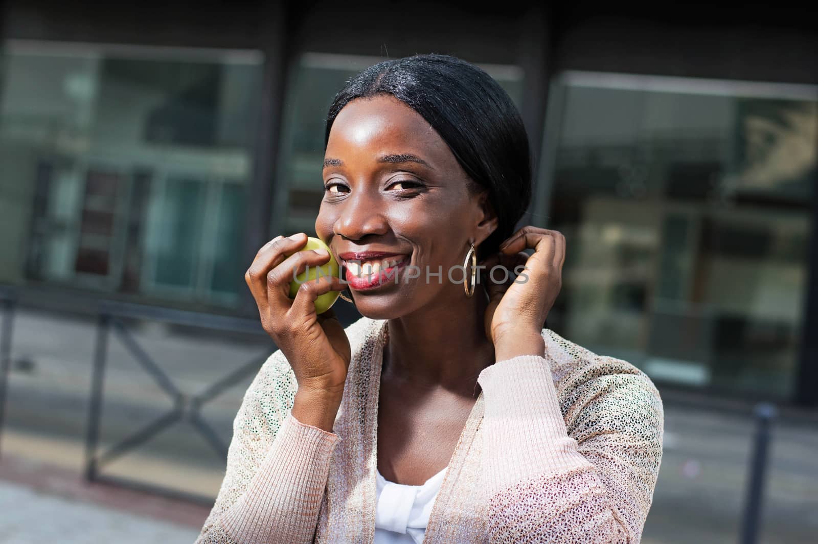 This young woman with a beautiful smile, stick an apple on her check.