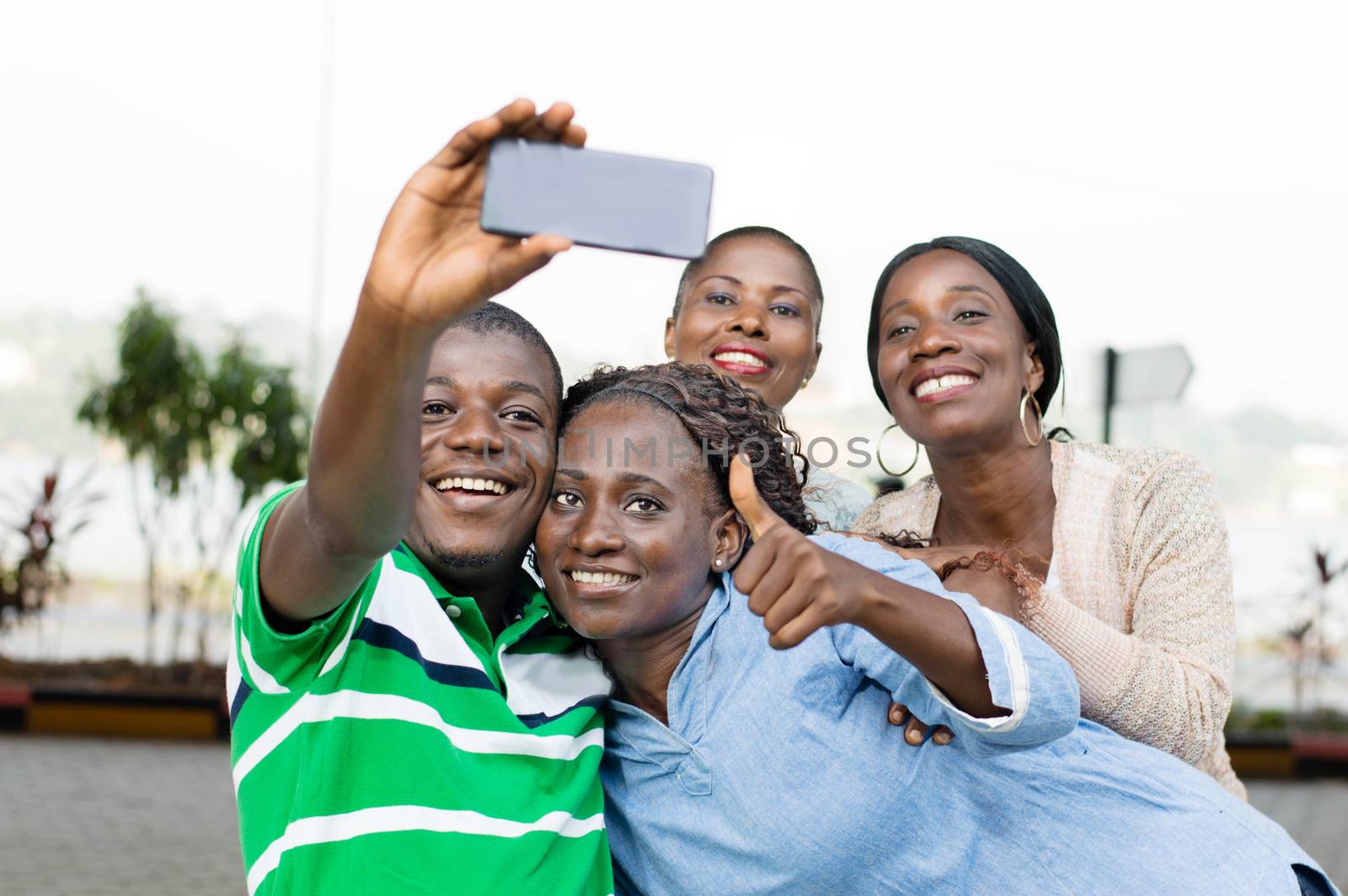 group of young people taking a picture with a mobile phone to mark their reunion.