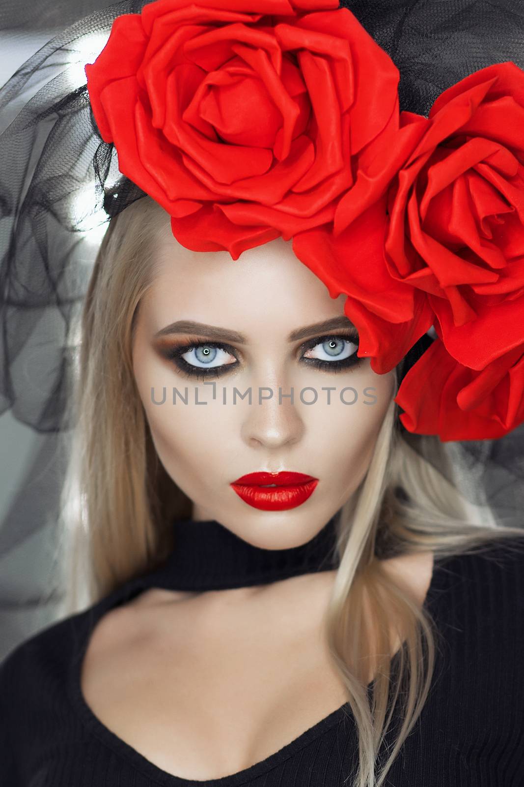 Attractive Goth female with bright makeup wearing amazing rose headgear and looking at camera