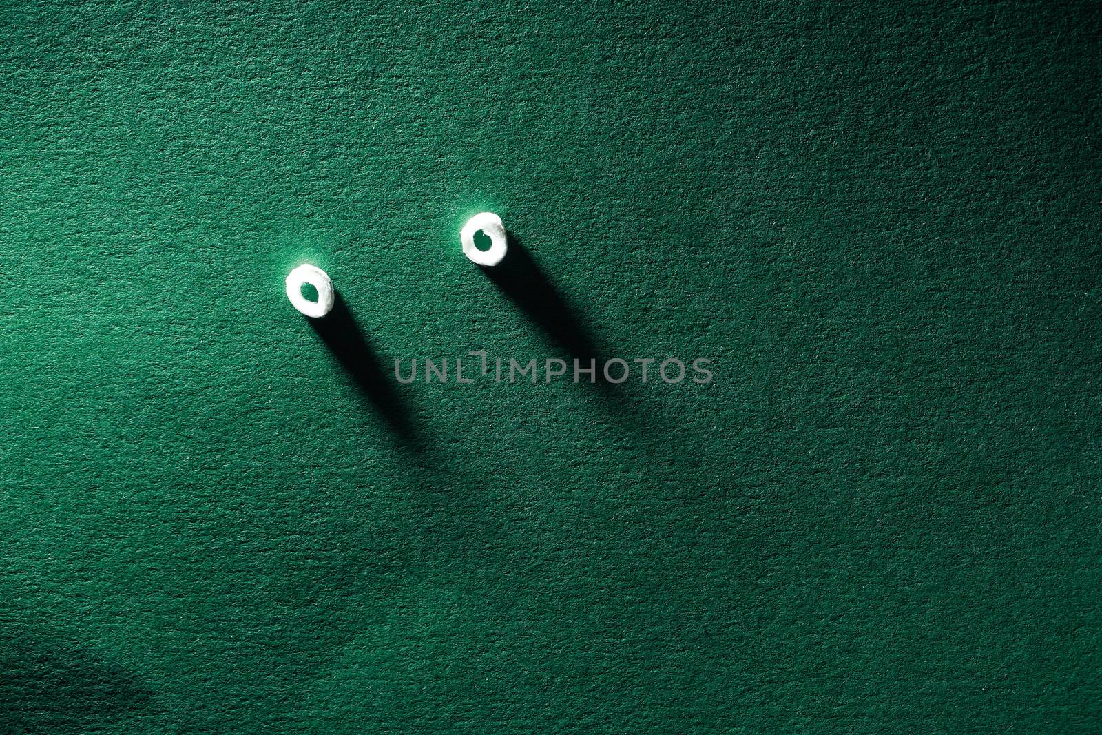 Spying concept. Pair of eyes looking from green paper wall