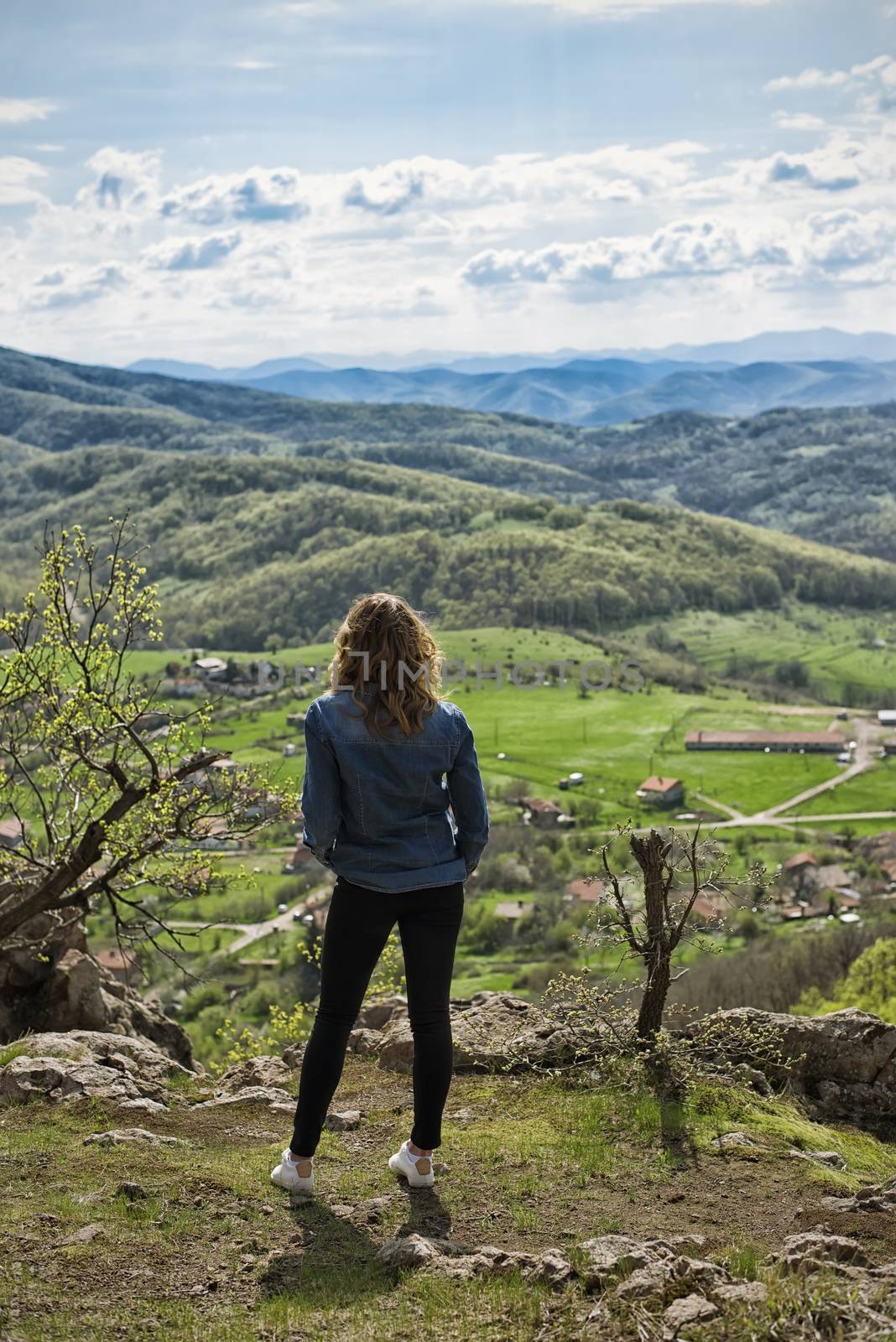 A hiking girl sits on the edge of the cliff and looking at the  valley and mountains by sevda_stancheva