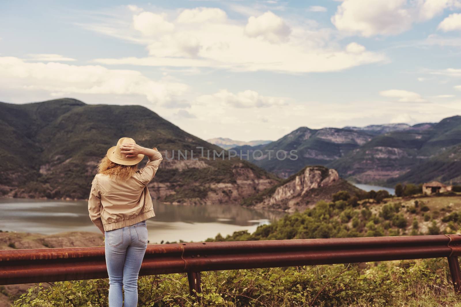 A hiking girl stands by the roadside and looking at the river and mountains. Location: the meanders of Arda river, Bulgaria by sevda_stancheva