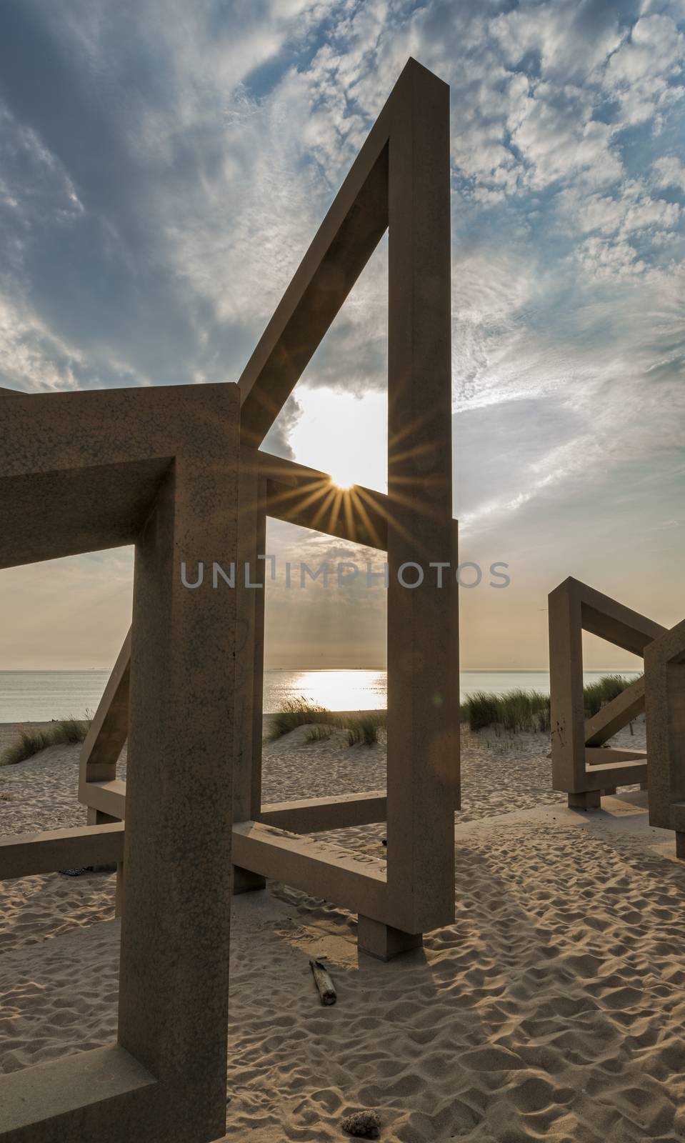 wooden structure on the beach with the clouds and sunset in the background, this is europoort maasvlakte beach in the evening