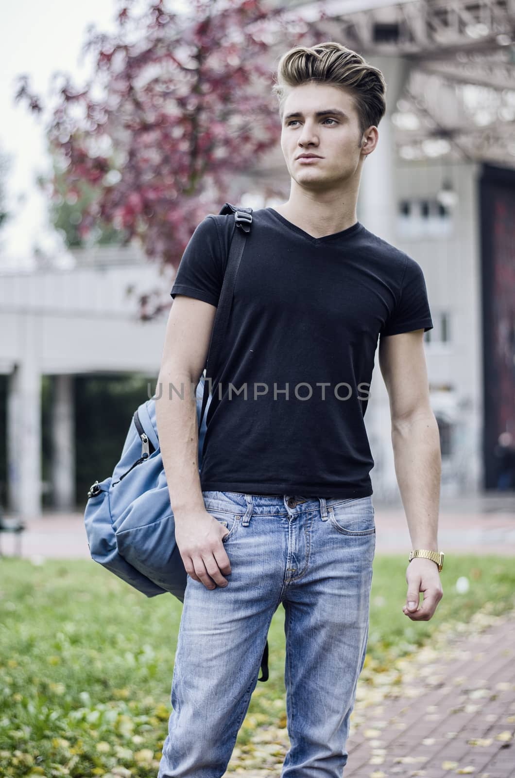 Young man standing in city environment, with backsack by artofphoto