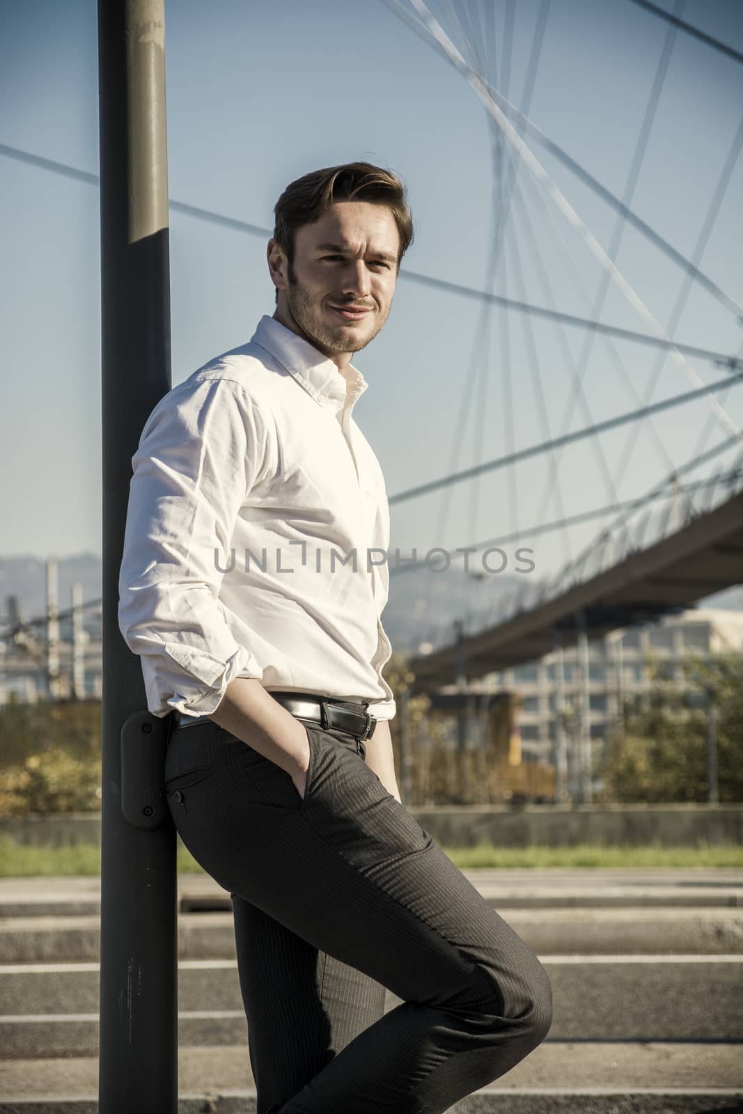 Handsome young man outside wearing white shirt, looking to a side. Profile view, day shot.