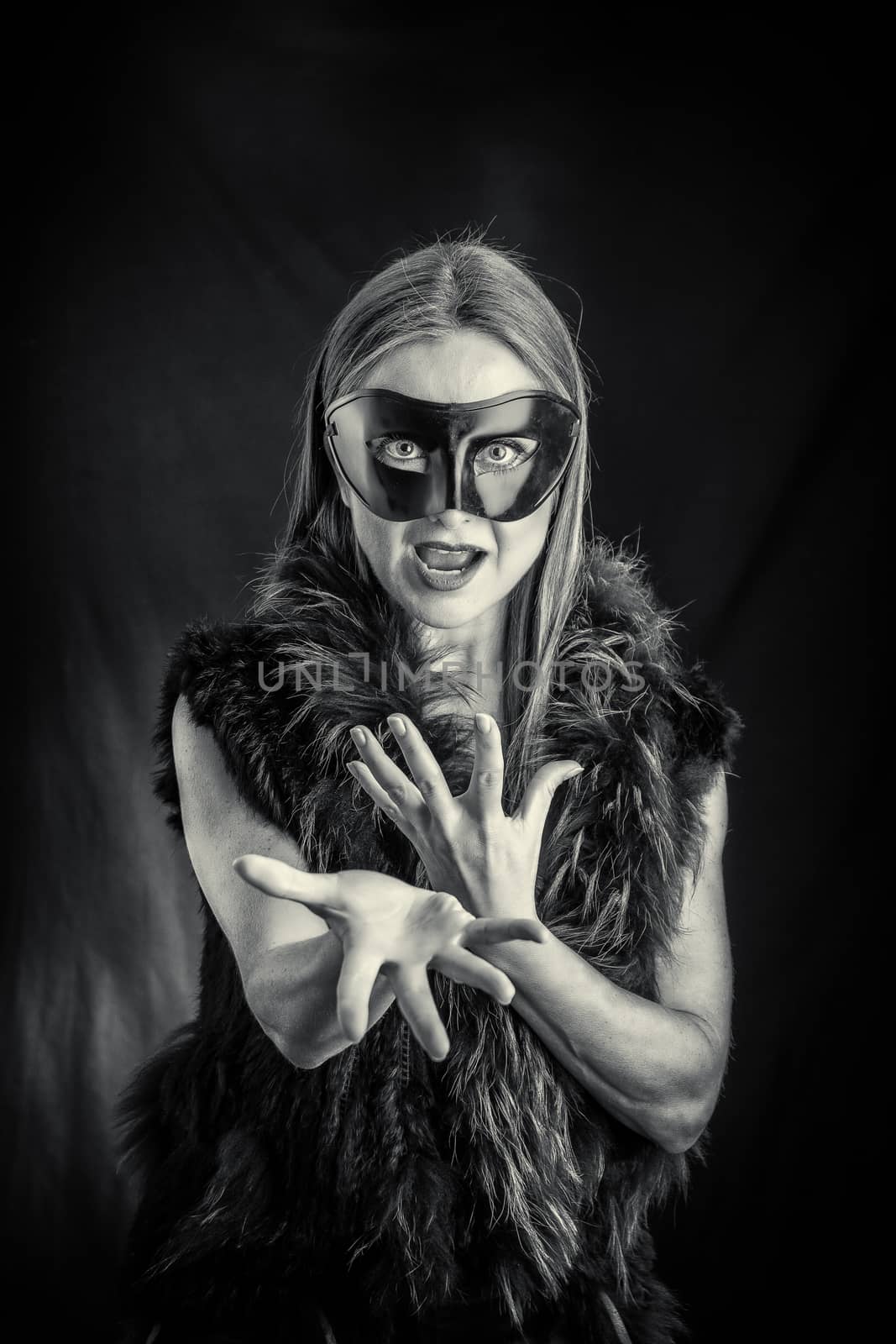 Woman in black mask performing in studio against black background