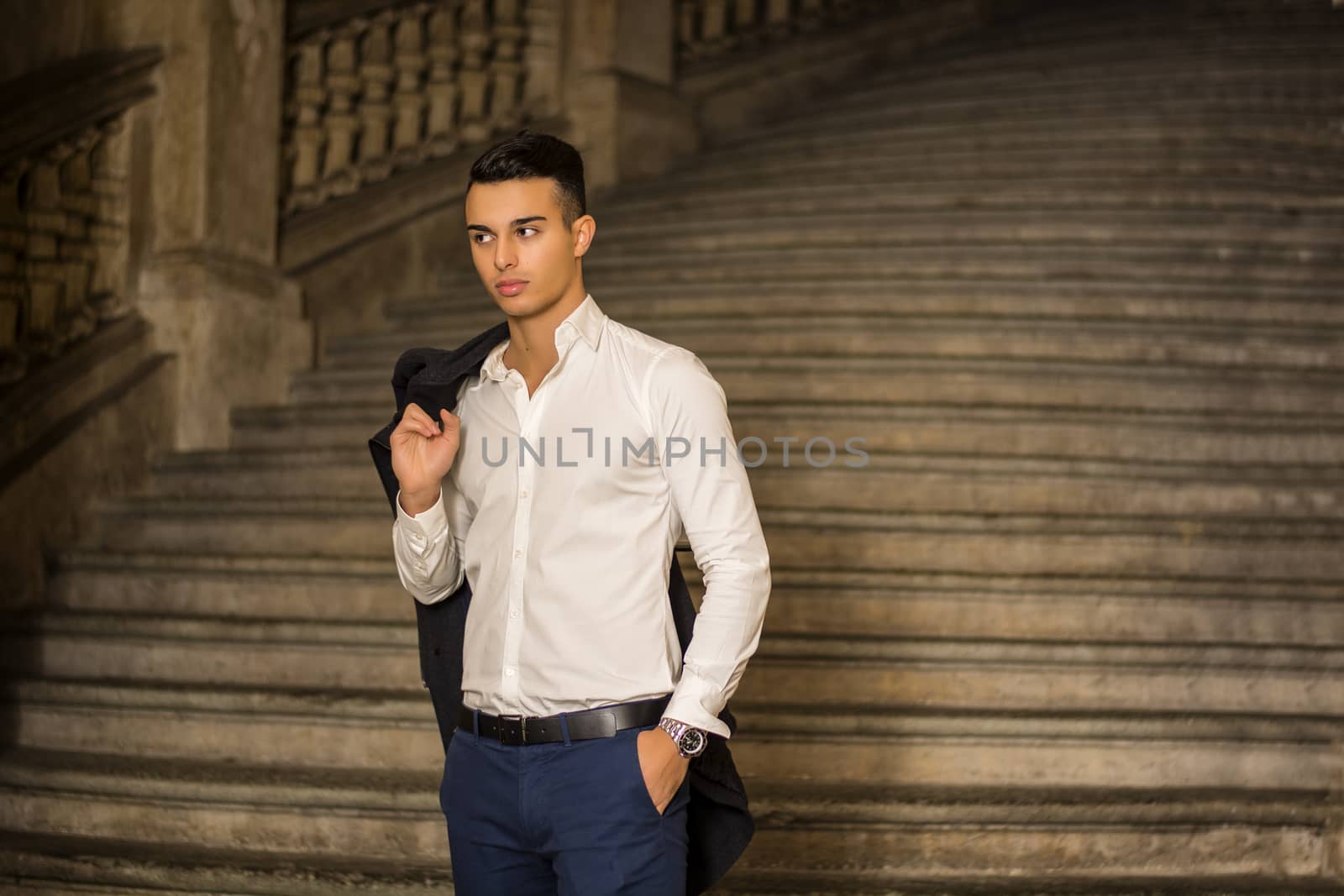 Elegant attractive young man outdoor wearing business suit, in European city on old stairs