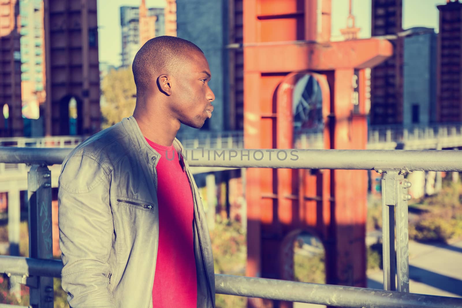 Portrait of a sexy young black man in urban environment wearing red shirt and grey leather jacket