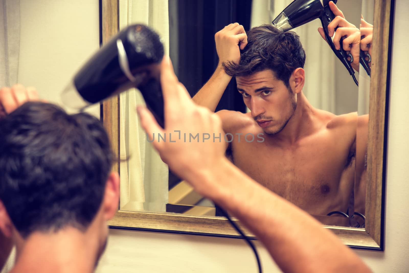 Shirtless young man drying hair with hairdryer by artofphoto