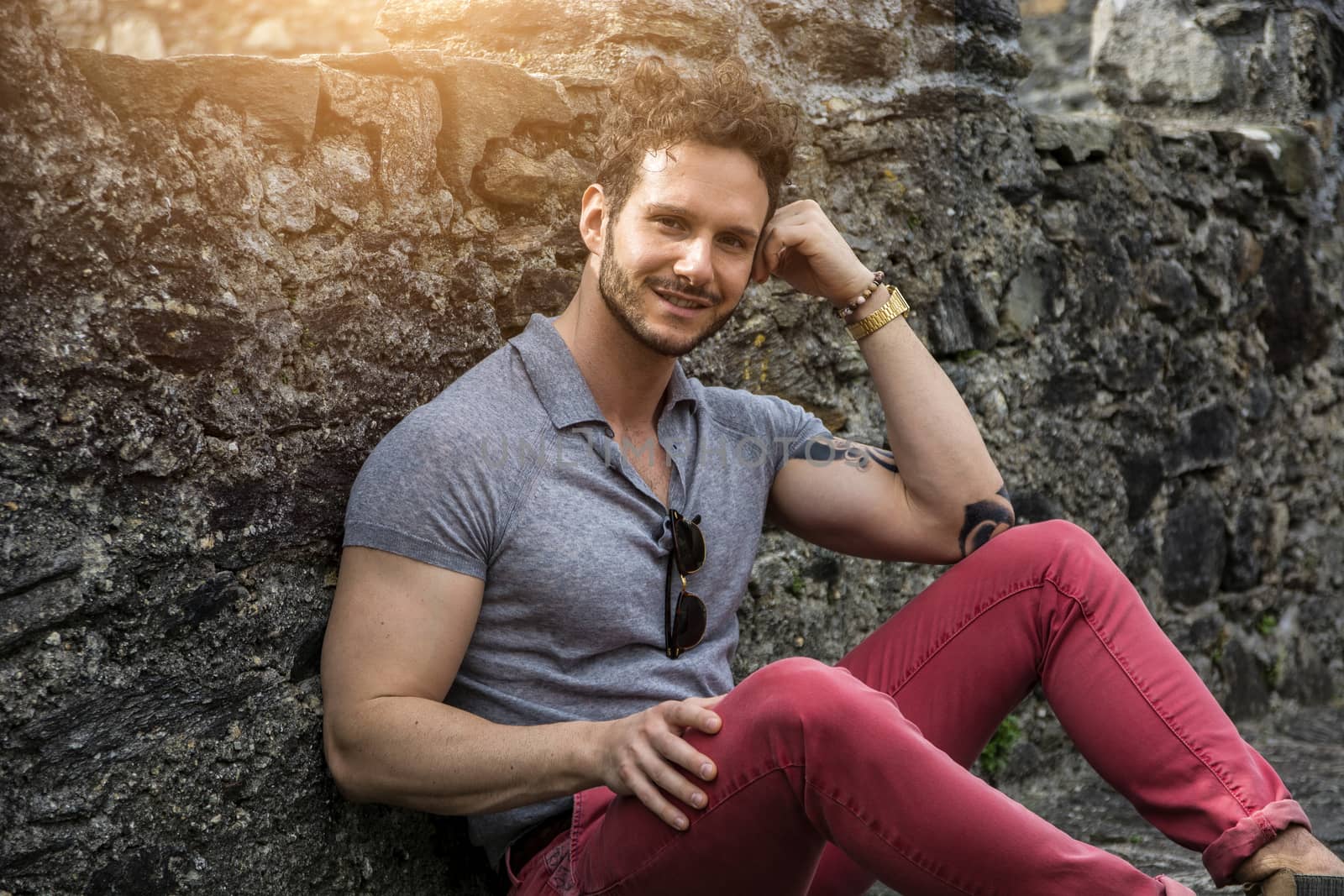 Attractive man outdoor in old European castle, in Switzerland. Athletic build, with tight t-shirt and sunglasses