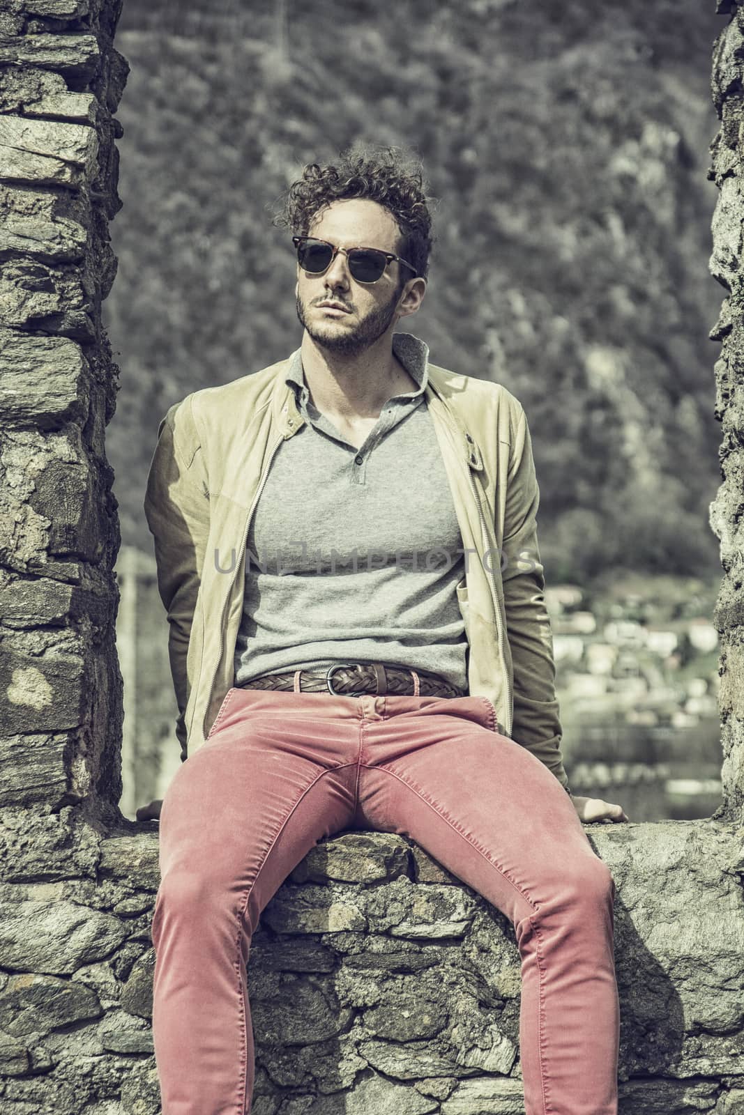 Attractive man outdoor in old European castle, in Switzerland. Athletic build, with tight t-shirt and sunglasses