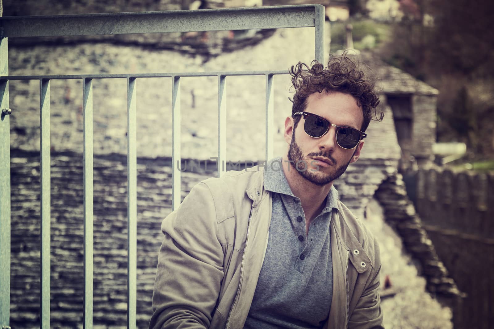 Attractive man outdoor in old European castle, in Switzerland. Athletic build, with tight t-shirt and sunglasses