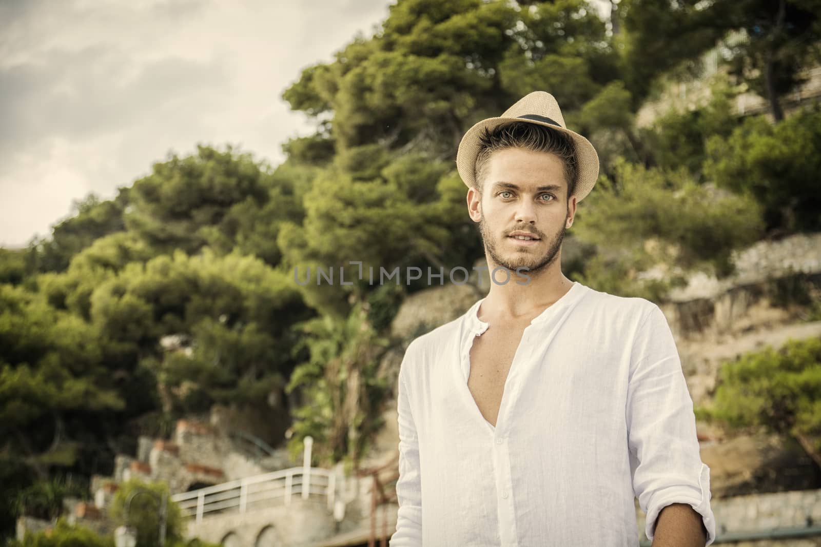 Handsome Young Man in Trendy Attire, Outdoor in Nature in a Sunny Summer Day Wearing a White Shirt