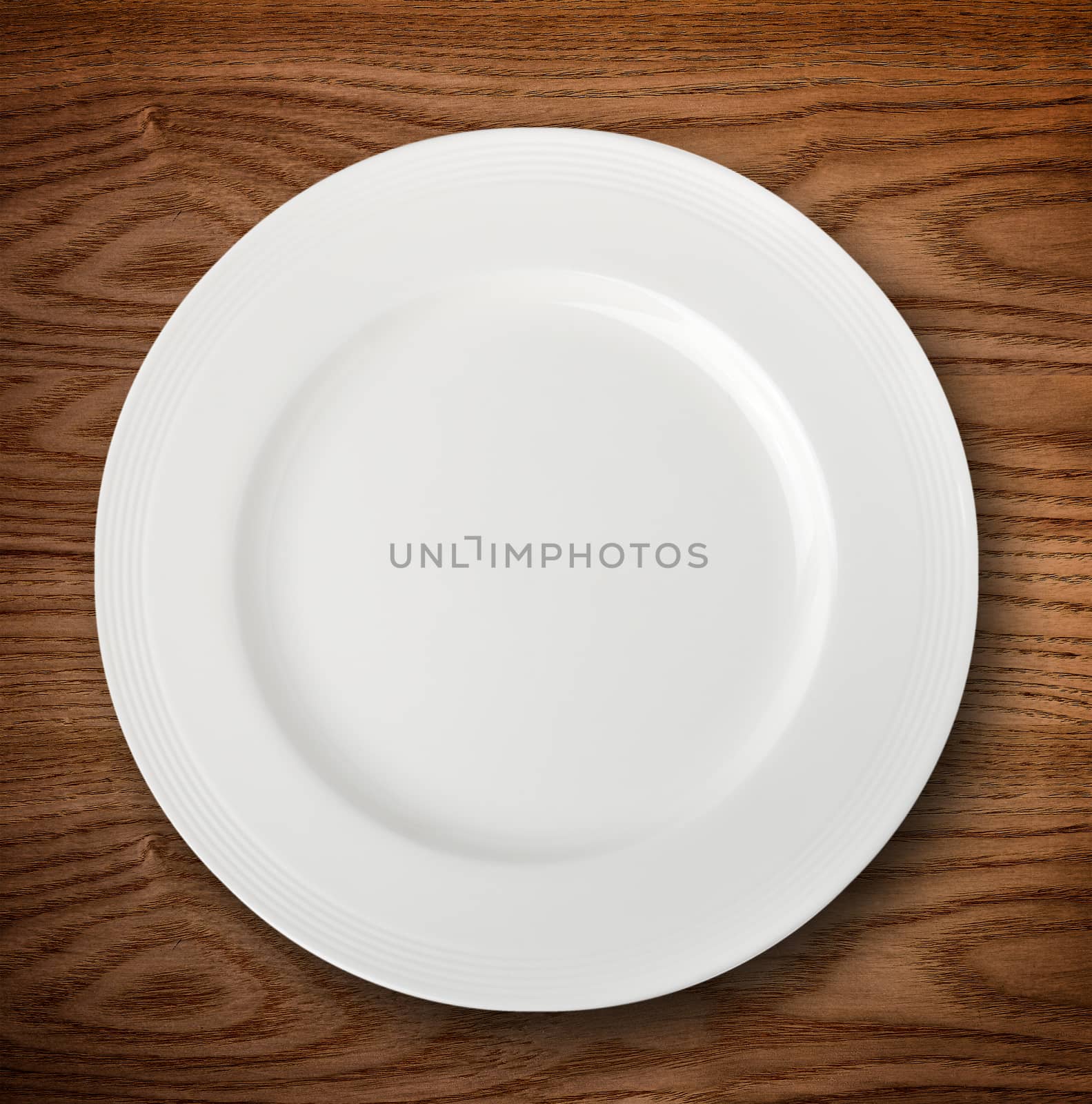 Empty white plate on wooden table by sommai