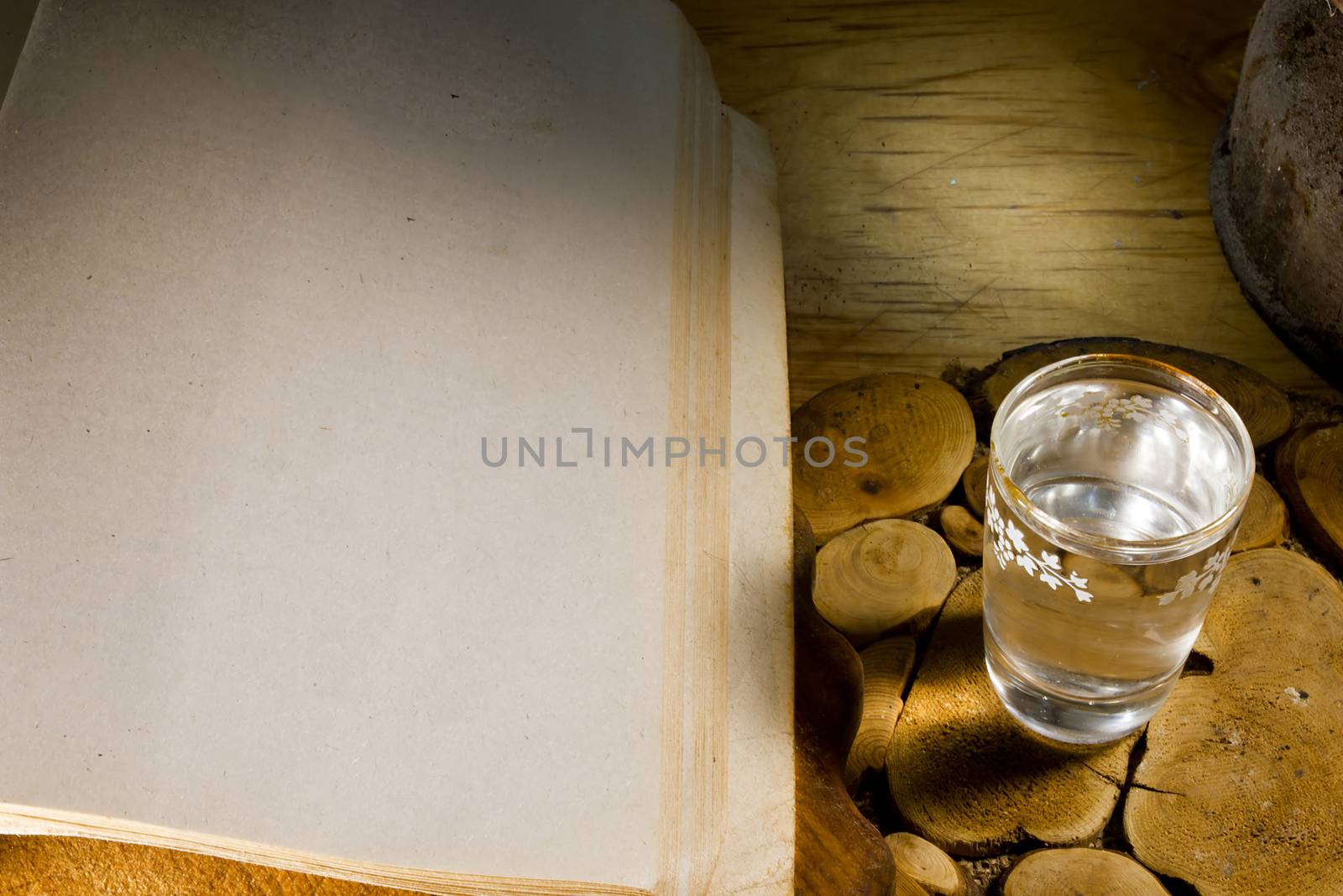 Glass of vodka and an ancient book on an old wooden table