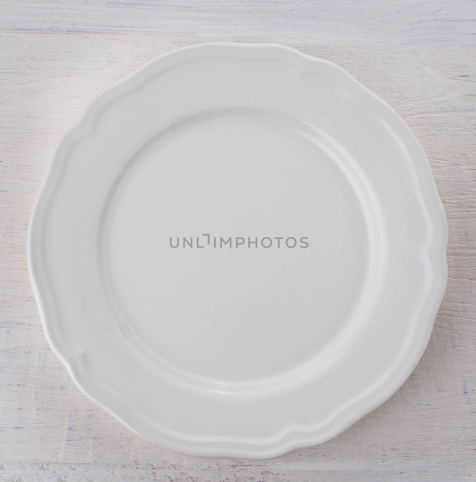 Empty white plate on wooden table by sommai