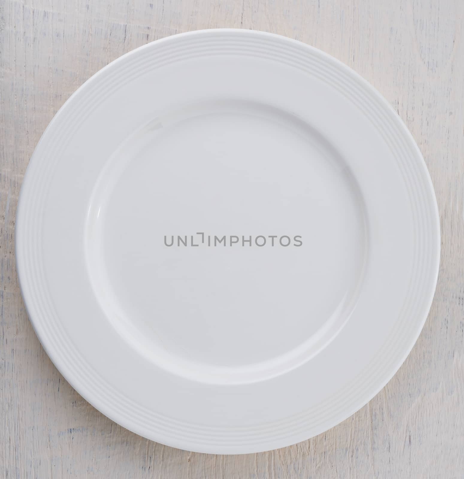 Empty white plate on wooden table by sommai