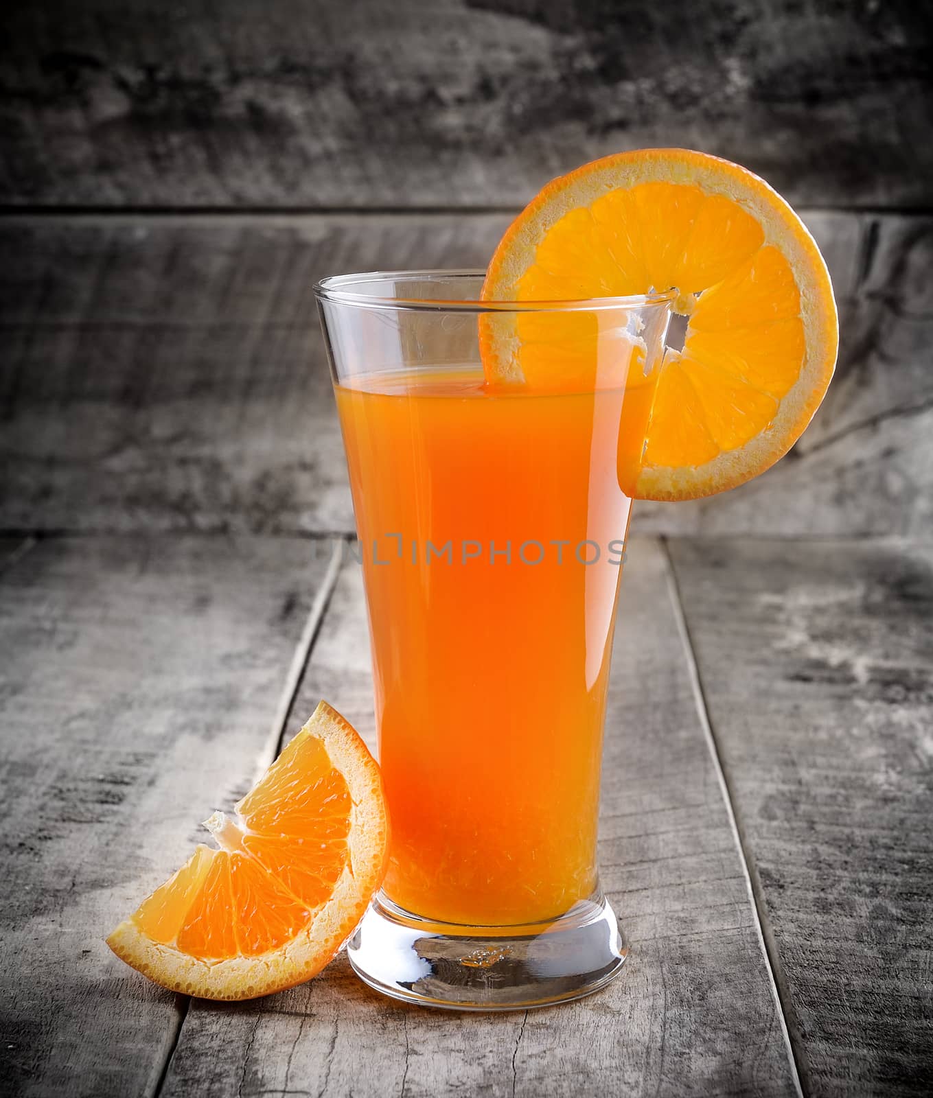 Orange juice glass and fresh oranges on wood
