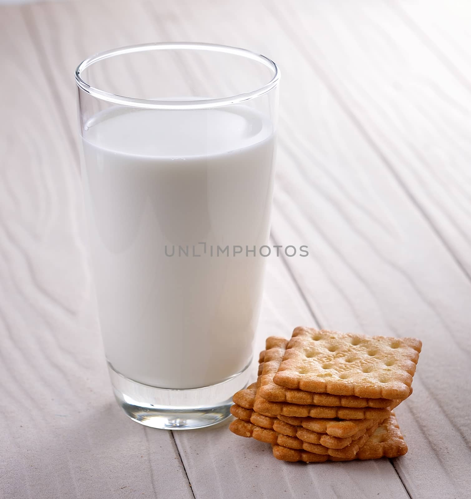 glass of milk and cracker on whitewood by sommai