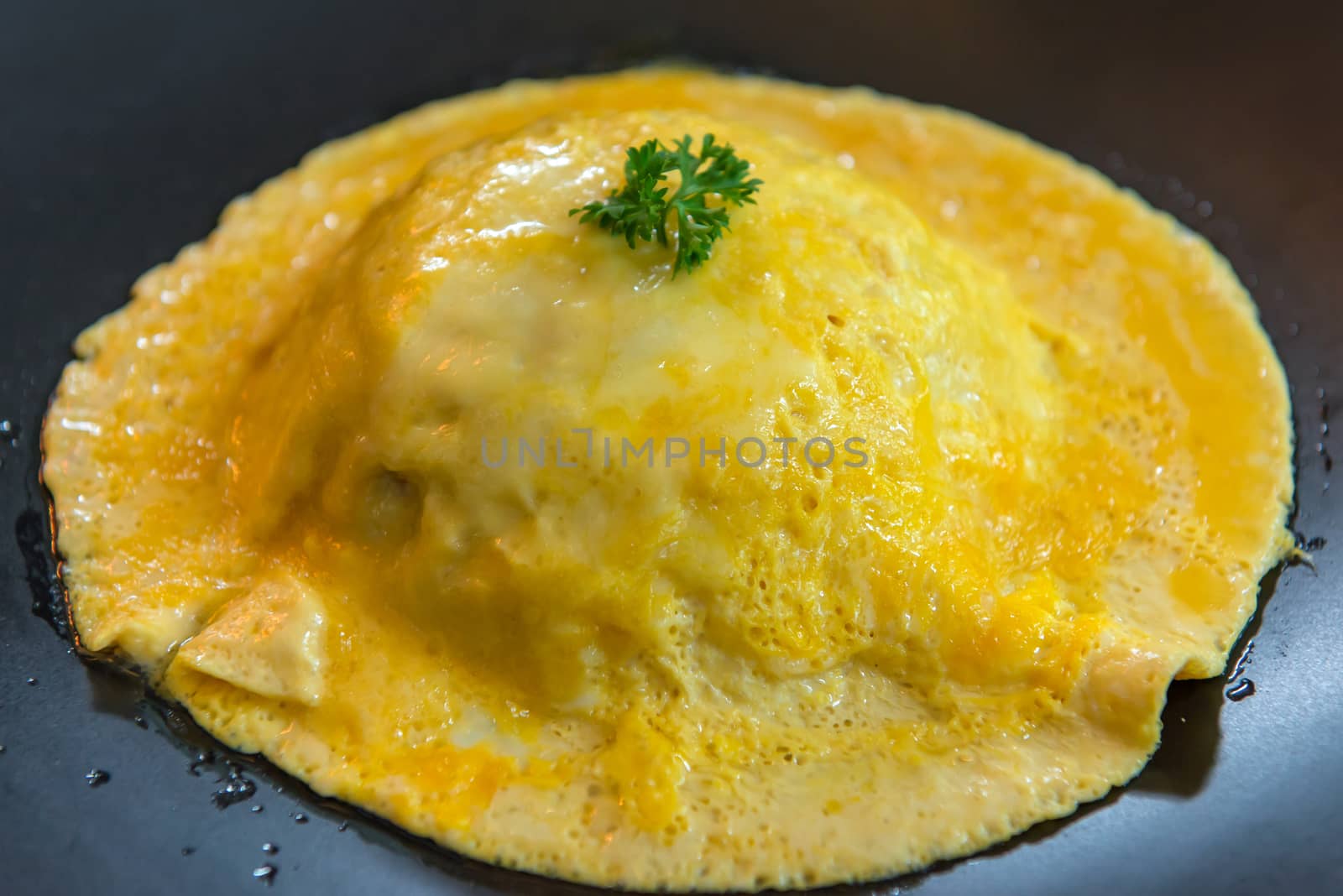 top view of rice with omelet on black dish.