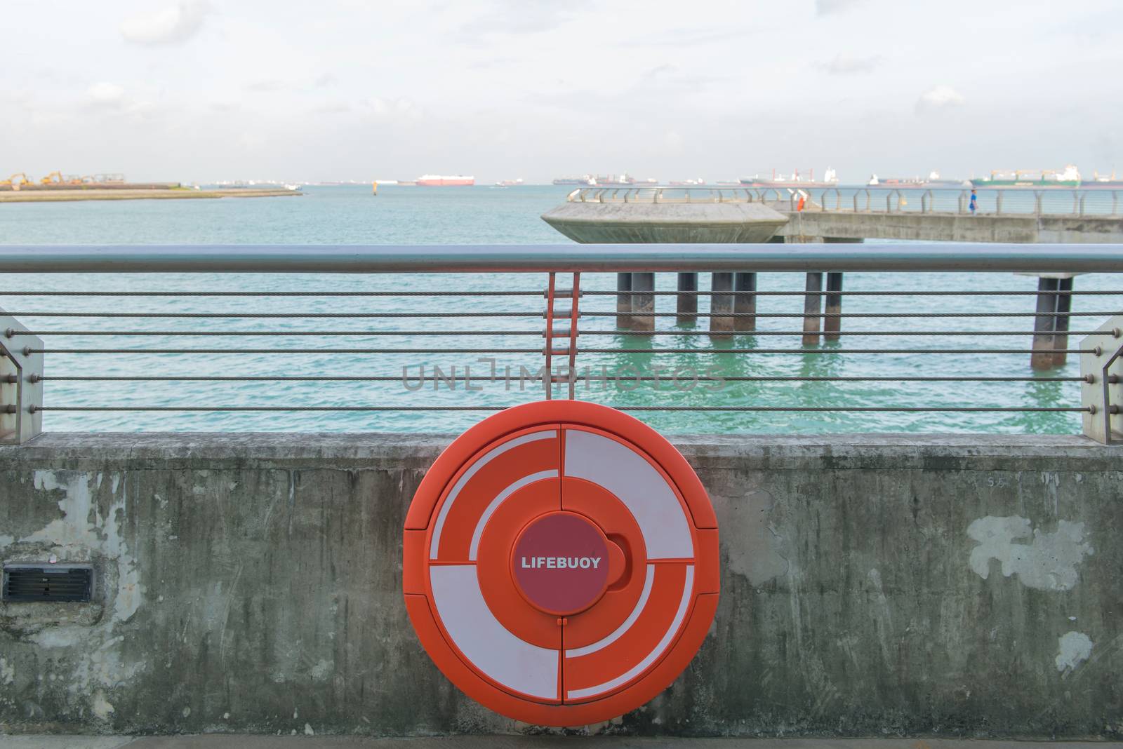 red Lifebuoy on railing by the sea.