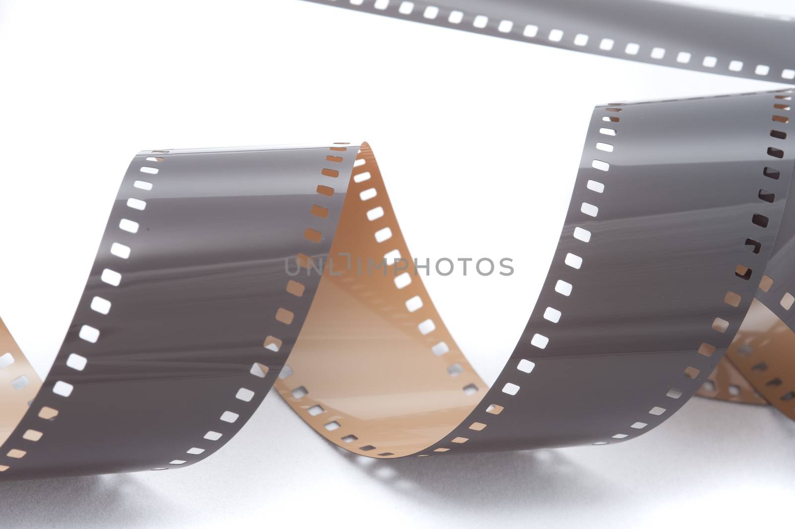 Grey 35 mm or photo film strip in spiral over white surface isolated background concept
