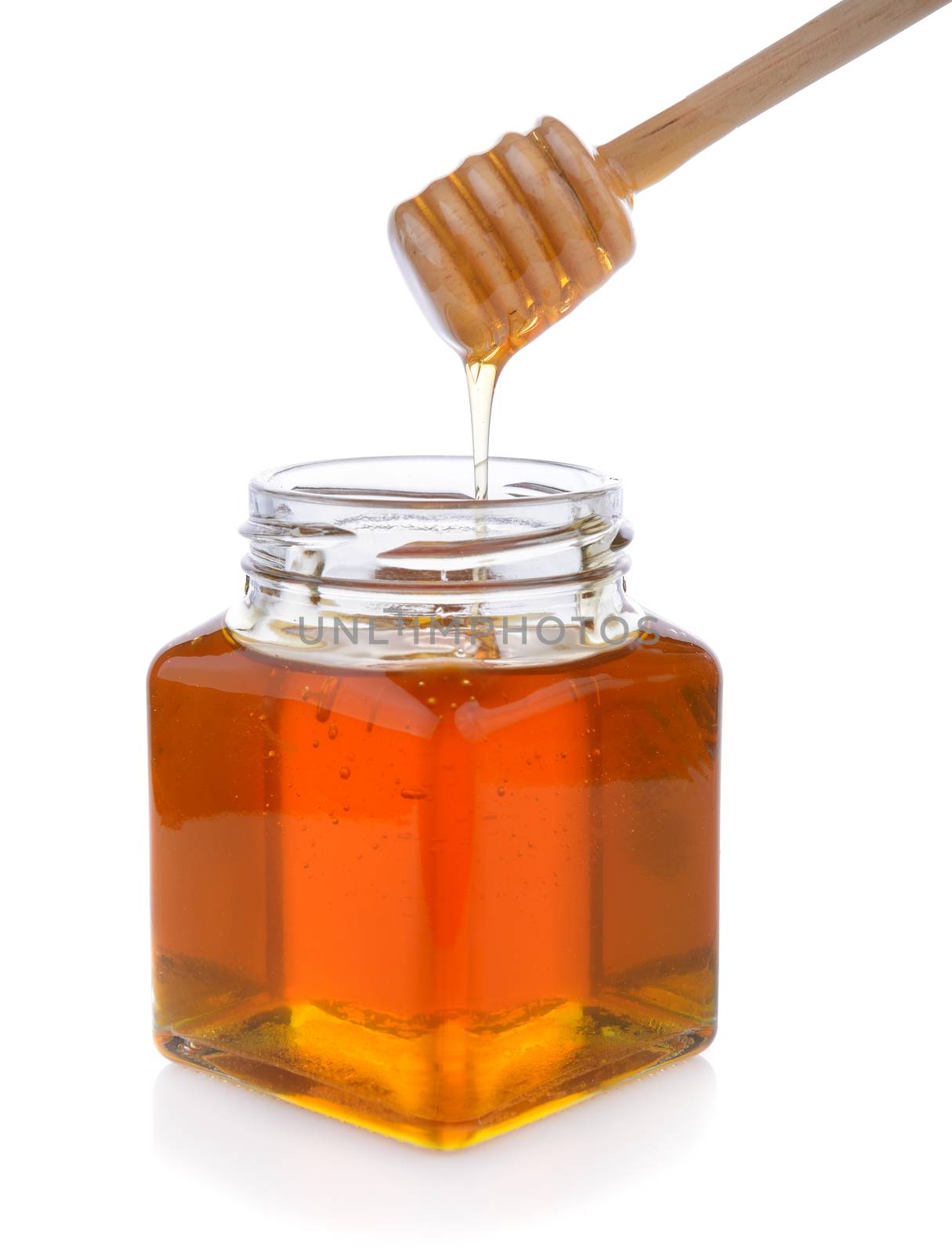 Honey with wooden honey dipper on jar by sommai