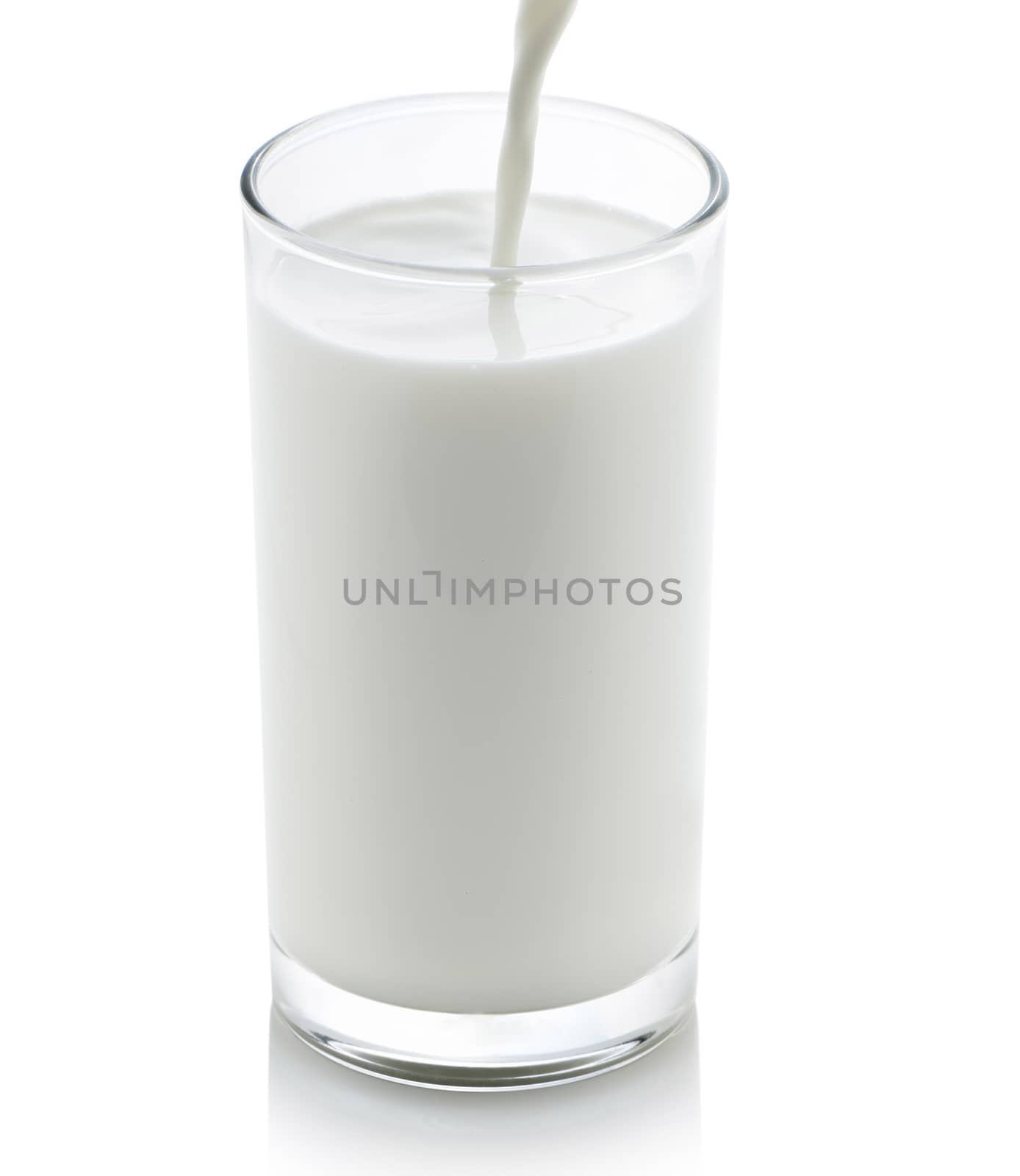 Milk pouring from a jug into a glass on white background