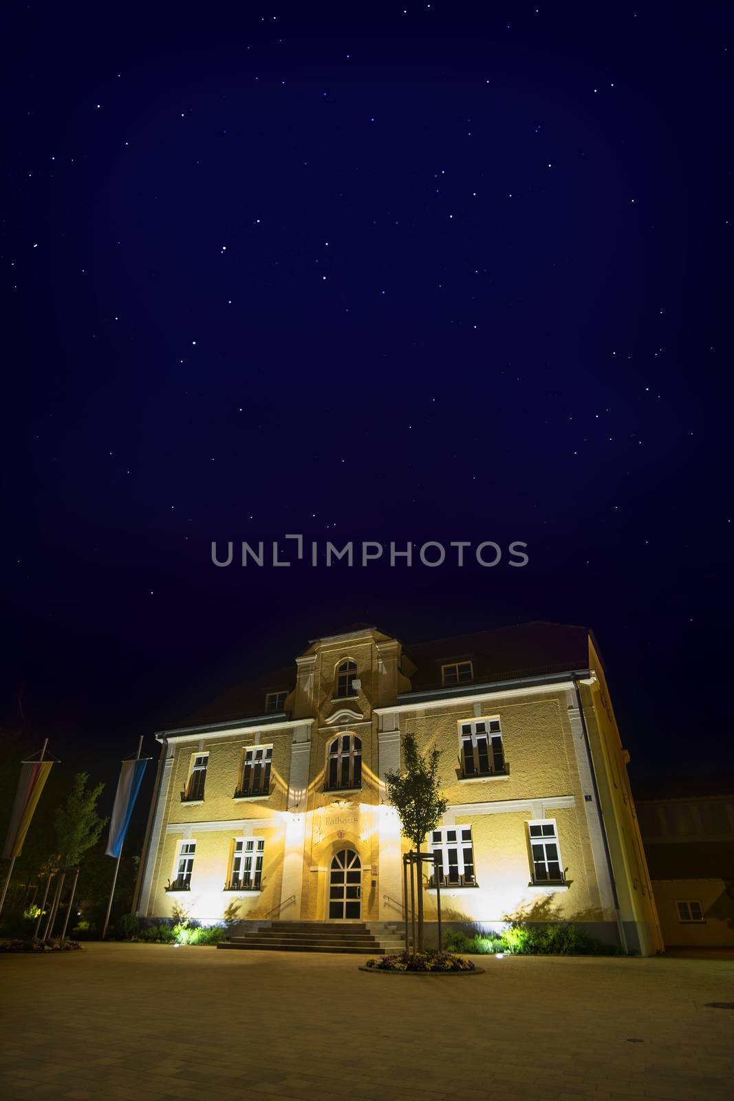 Illuminated townhall in village Maisach in Bavaria, Germany at night with stars in the sky