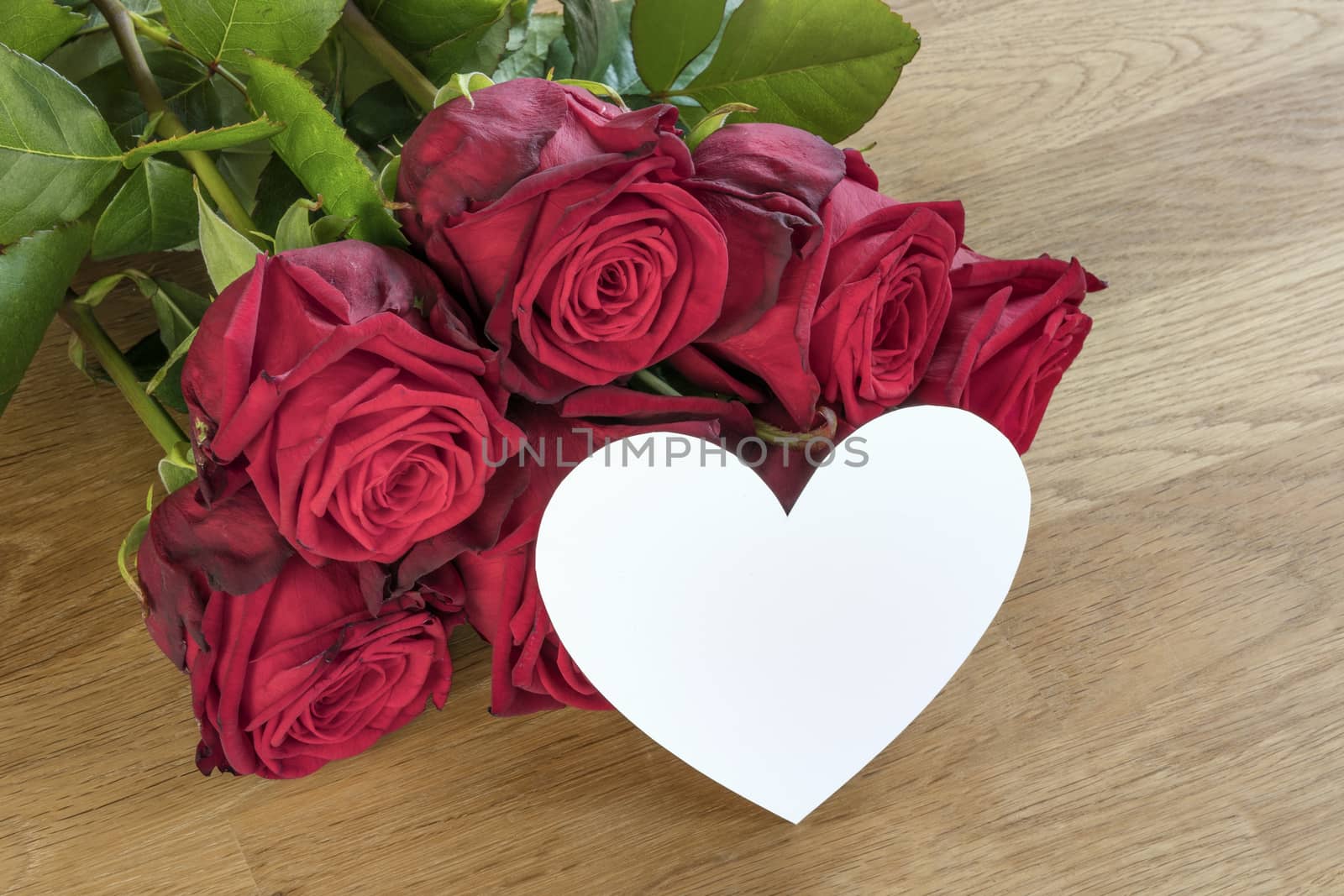 Red roses on a wooden table with white heart