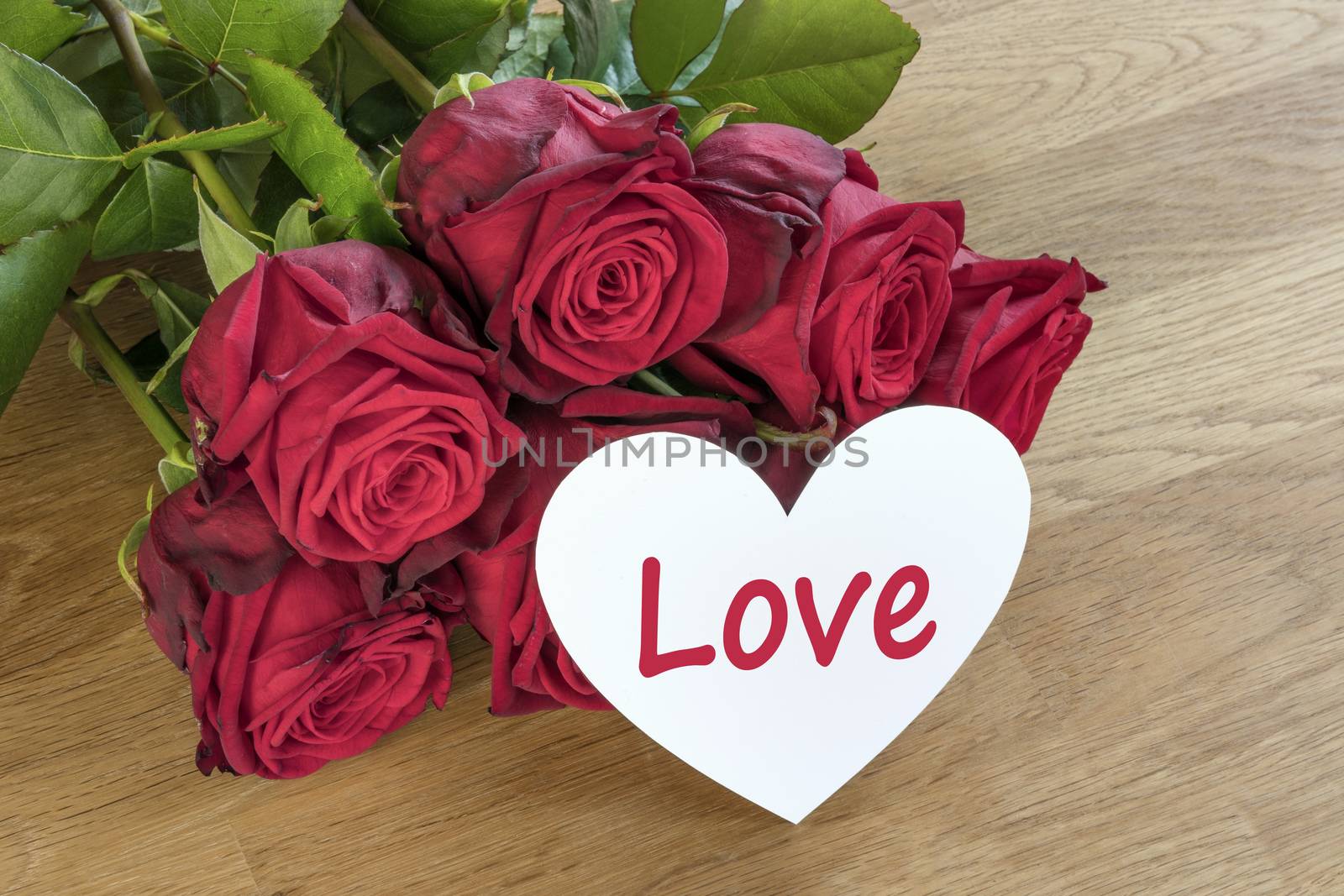 Red roses on a wooden table with white Love heart