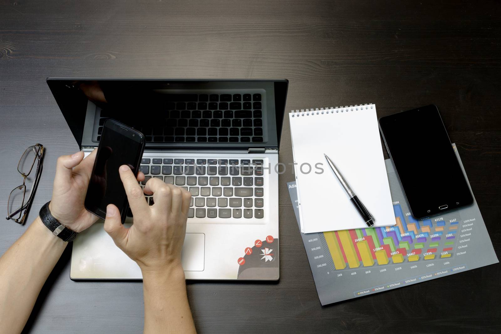 A man prints on a laptop, lying next to the phone, tablet glasse by rdv27