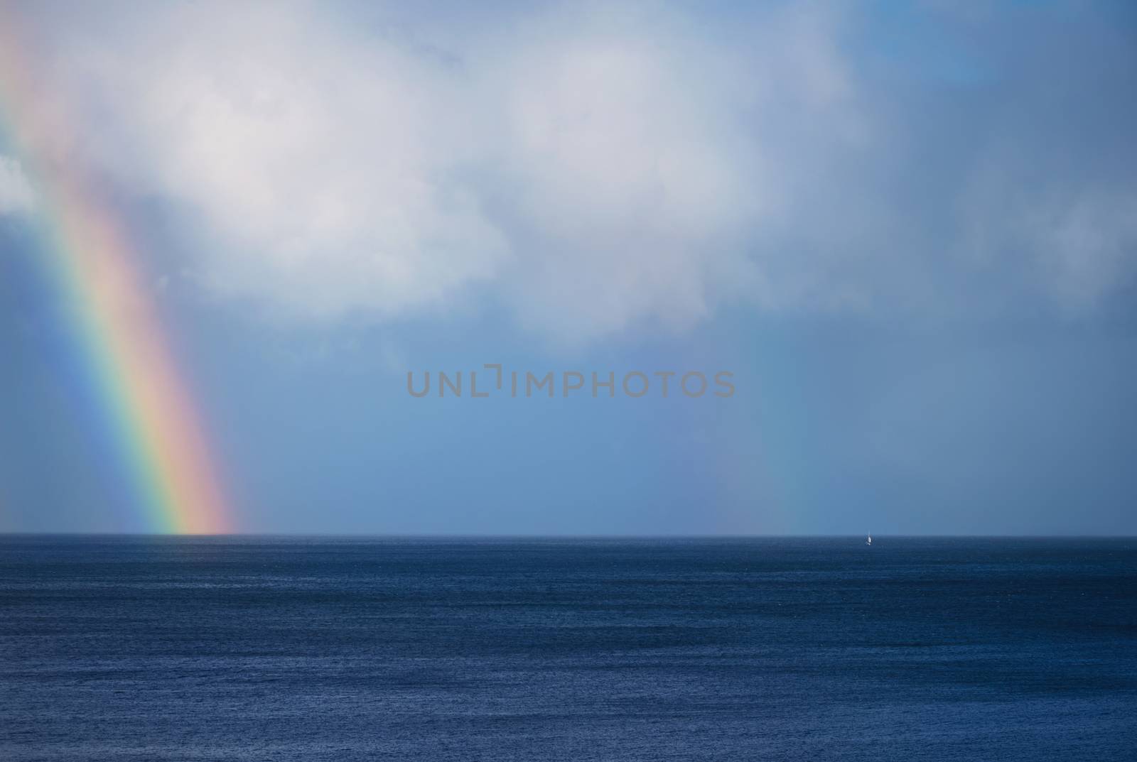 Beautiful rainbow and boat on the ocean horizon