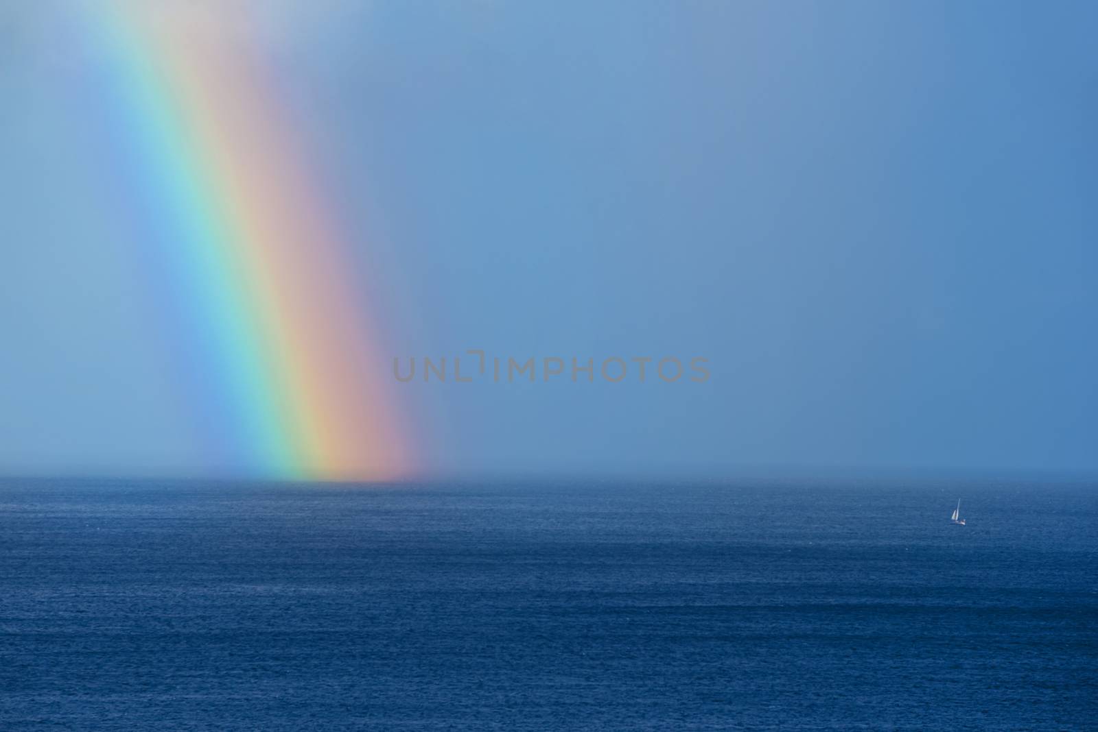 Beautiful rainbow and boat on the ocean horizon